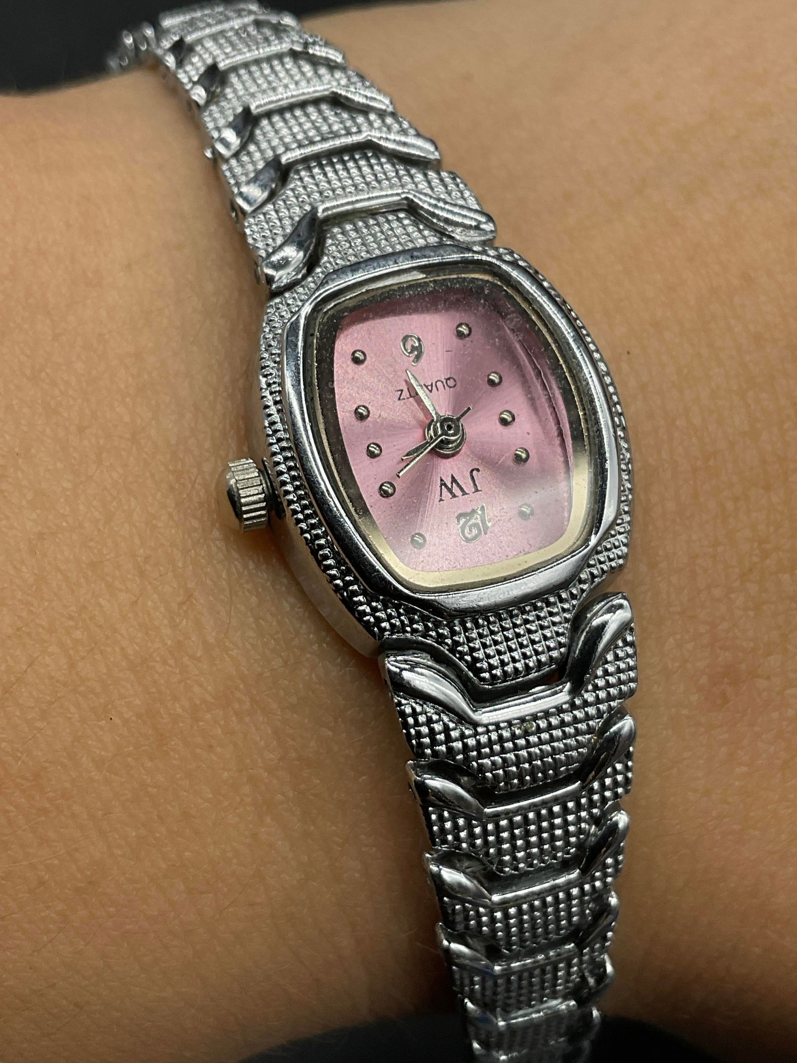 JW QUARTZ Pink Faced Silver Tone Metal Wristwatch: JW QUARTZ Pink Faced Silver Tone Metal Wristwatch. Reverse reads Stainless Steel Back. Length measured end to end approx. 6.5 inches. Box clasp closure. Not tested for function. Surface wear consisten