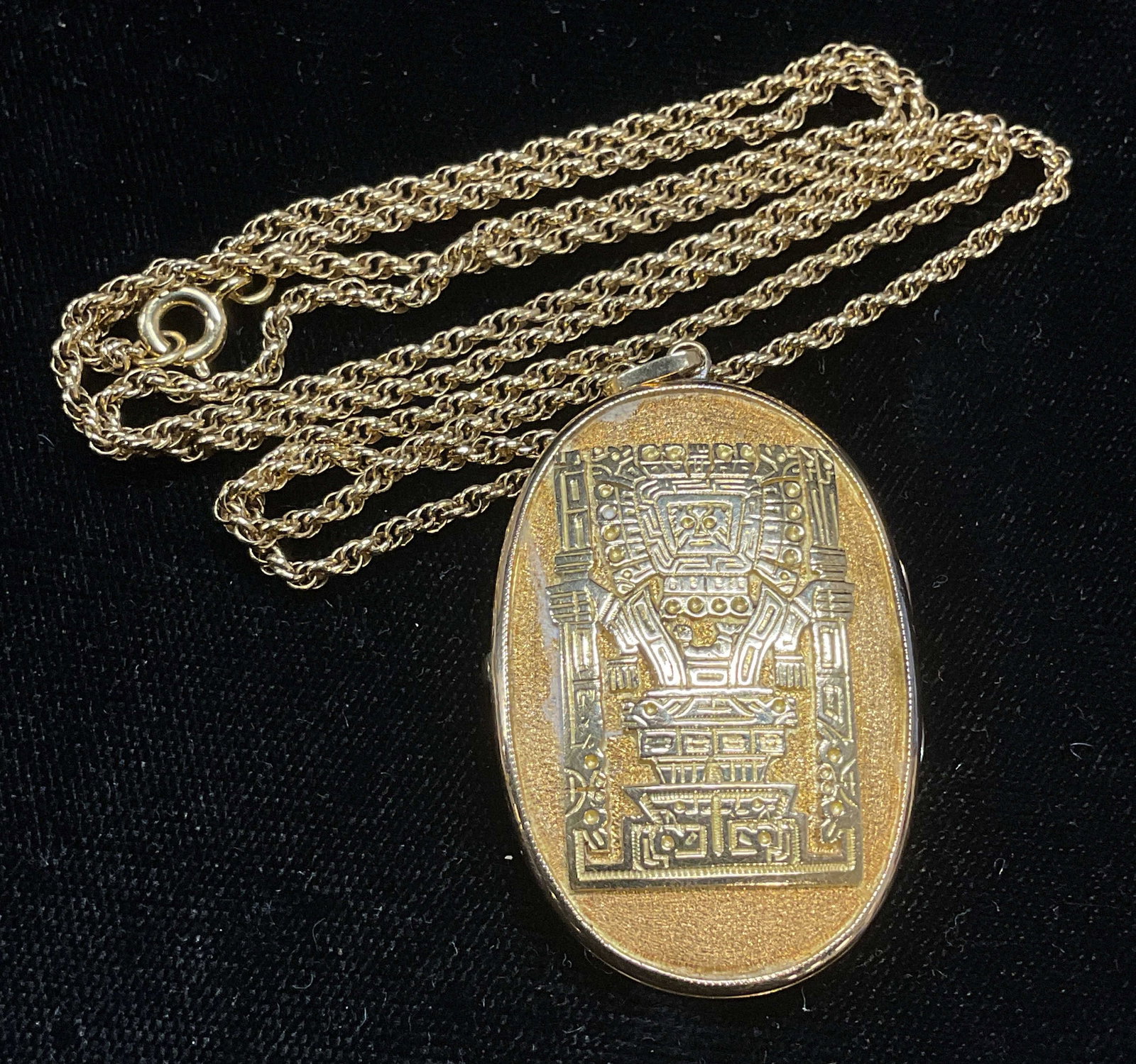 Gold Tone Aztec Motif Locket Necklace: Gold tone chain necklace with locket pendant. Raised Aztec motif. Drop length approx 13 inches. Locket approx 1 5/8 x 1 inches. Some wear including scratching observed. Jewelry, estate jewelry, costum