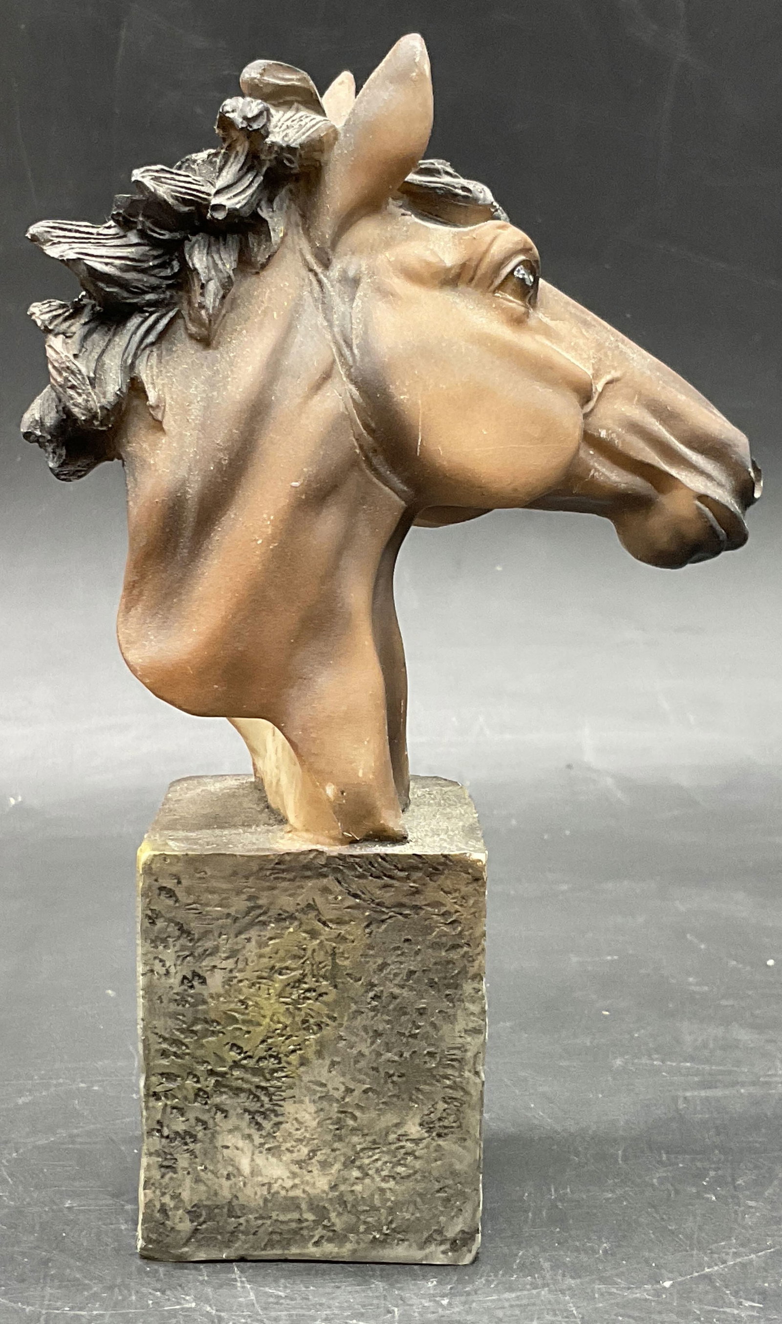 Brown Horse Head Bust Figural: Horse Head Bust Figural. Brown hues to the horse. The head is attached to a rectangular base. Crafted from a resinous material. Measures approx. 5H x 3.25W in. Surface wear, losses to finish, and disc