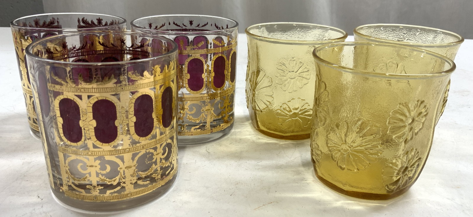 MCM 6 Culver Cranberry & Yellow Depress Gls Cups: Lot includes 6 cups. Three appear to be Culver (Mid century modern) with ornate gilt and cranberry tone detail. Three are yellow toned depression glass with floral and leaf detail. Each cup is glass. 