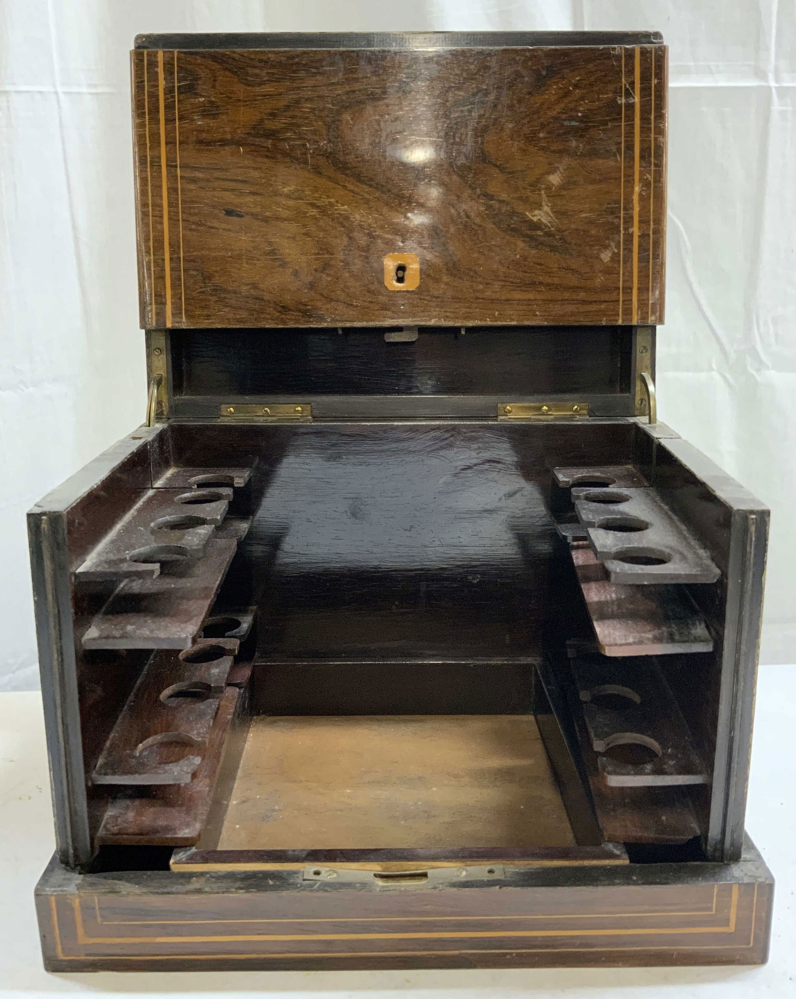 Vintage Inlaid Wooden Cordial Cabinet: Cabinet is vintage and wooden. Piece has inlaid detail. Front of piece folds into hinged lid. Interior has wooden racks to hold cordial glasses. Front of piece has key holes. Measures approx 12 inches
