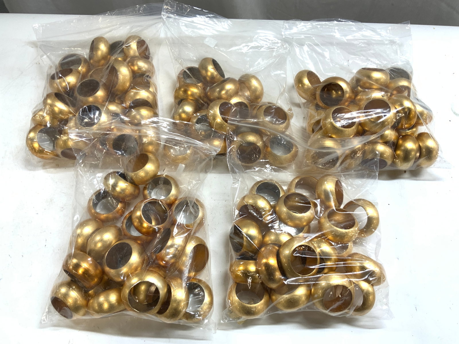 Set 100+ Gilt Resin Napkin Rings: Lot includes 100+ napkins rings. Each are gilt resin. Napkin rings each have circular forms. Napkin rings each measures approx 2.25 inches wide 1 inch deep. Napkin rings, gilt resin napkin rings, tabl