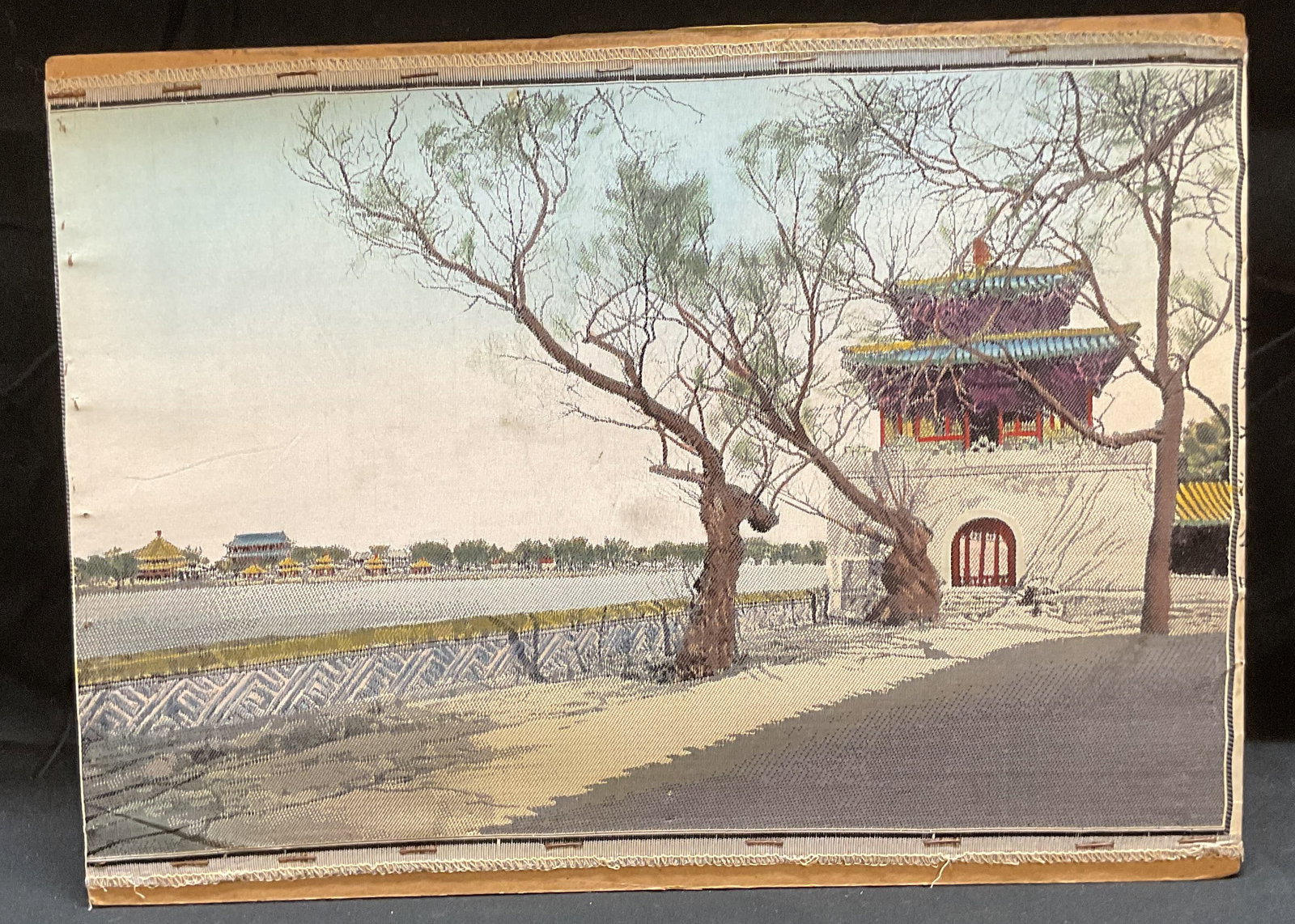 Asian Street Scene Woven Textile: Woven textile affixed to board. Asian street scene with view of pagoda, water, and city. Board measures approx 11.5 x 15.75 inches. Some wear consistent with exposure. Art, textile art, woven textile,