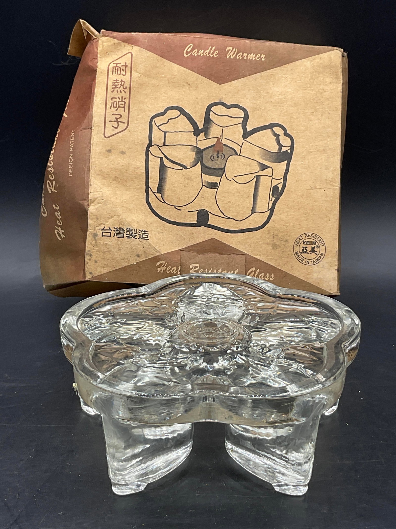 YAMA Heat Resistant Glass Candle Warmer, Org Bx: YAMA Heat Resistant Glass Candle Warmer. The glass candle warmer has a floral shape. Measures approx. 2.25H x 6W in. Underside reads YAMA TAIWAN. Packaging has evident wear and losses. home decor, hom