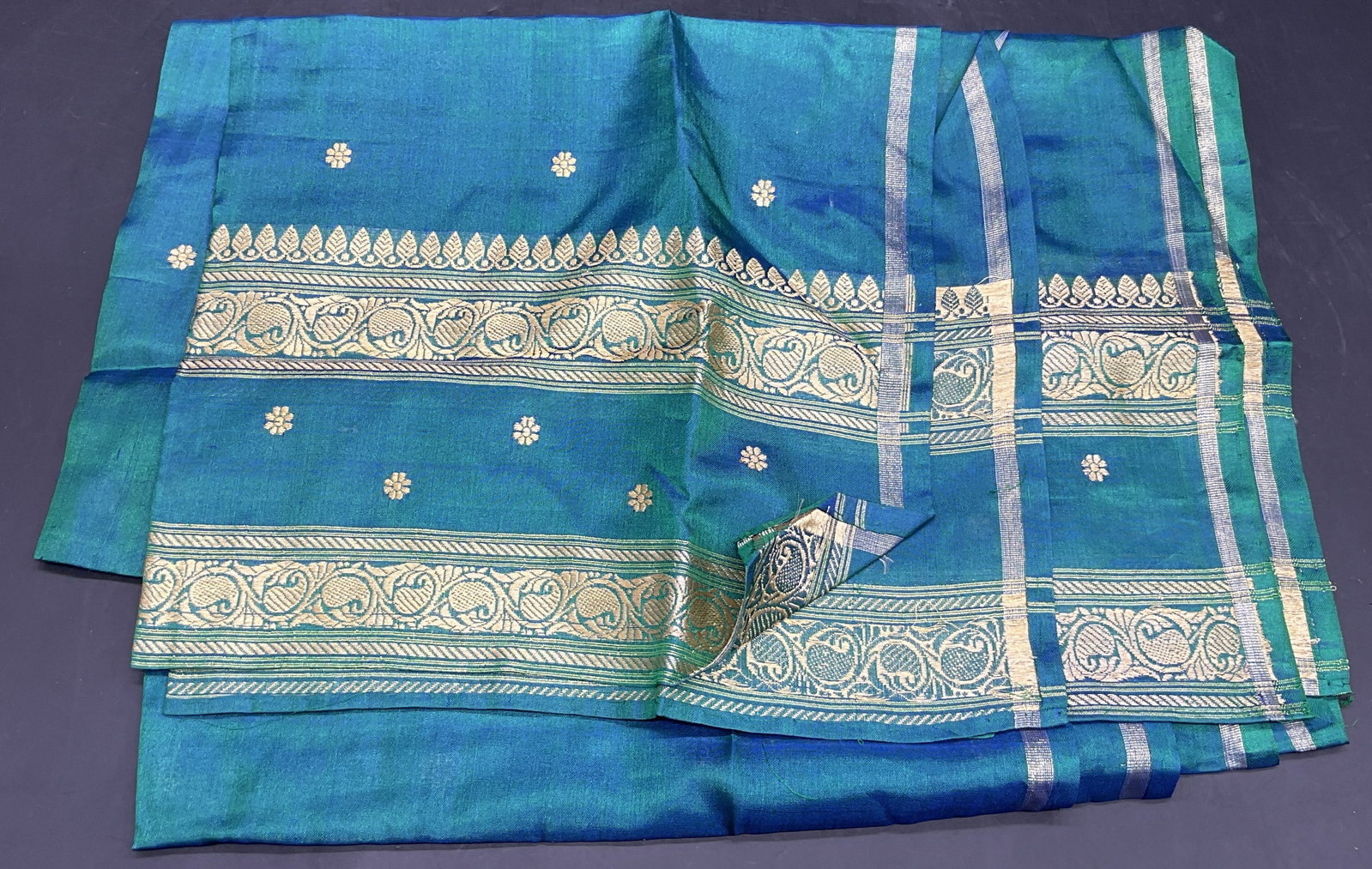 Vintage Handwoven Floral Motif Scarf / Shawl: The scarf features embroidered foliage motifs and floral patterns. Gold tone, teal, blue, and green hues throughout. Crafted from soft hand material. Measures approx. 66W x 19L in. Surface wear, loose