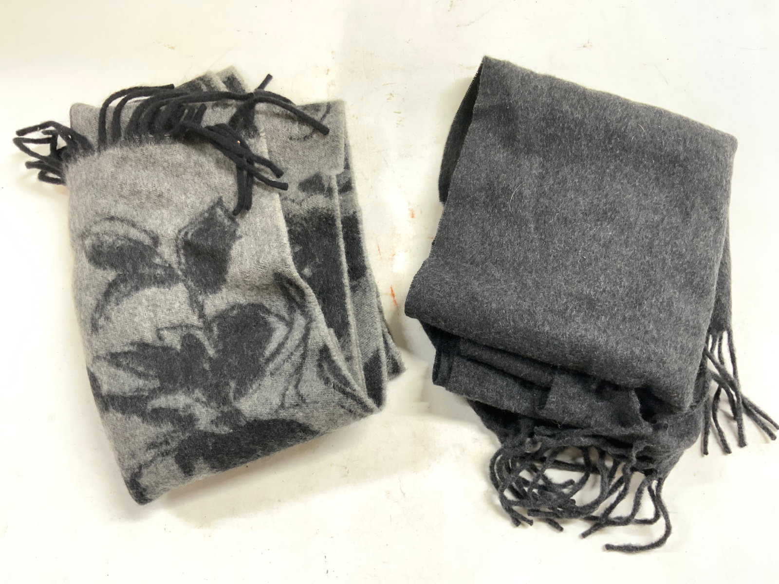 LORD & TAYLOR & J CREW Fringed Cashmere Scarves: Lot includes 2 scarves. Each are cashmere. One trademarked LORD & TAYLOR, the other trademarked J CREW. One solid dark slate, the other slate with black toned floral and leaf detail. Scarves each have