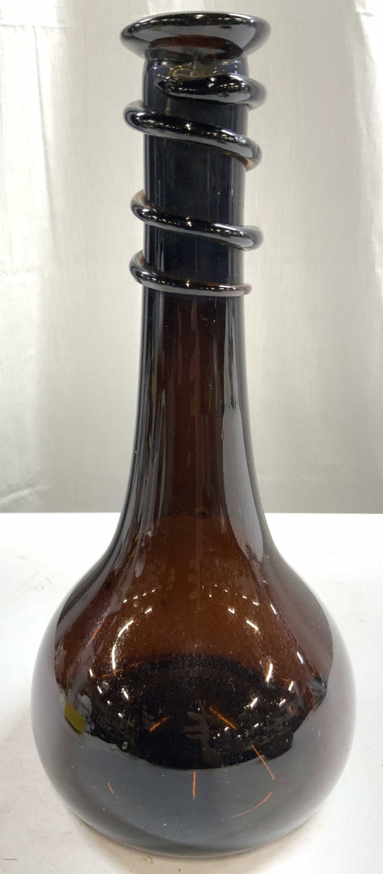 Vtg Handblown Persian Amber Glass Decanter: Decanter is hand blown due to pontil on underside. Piece has a dark amber tone. Persian amber glass decanter with coil detail around neck. Vessel tapers inward towards mouth. Decanter measures approxi