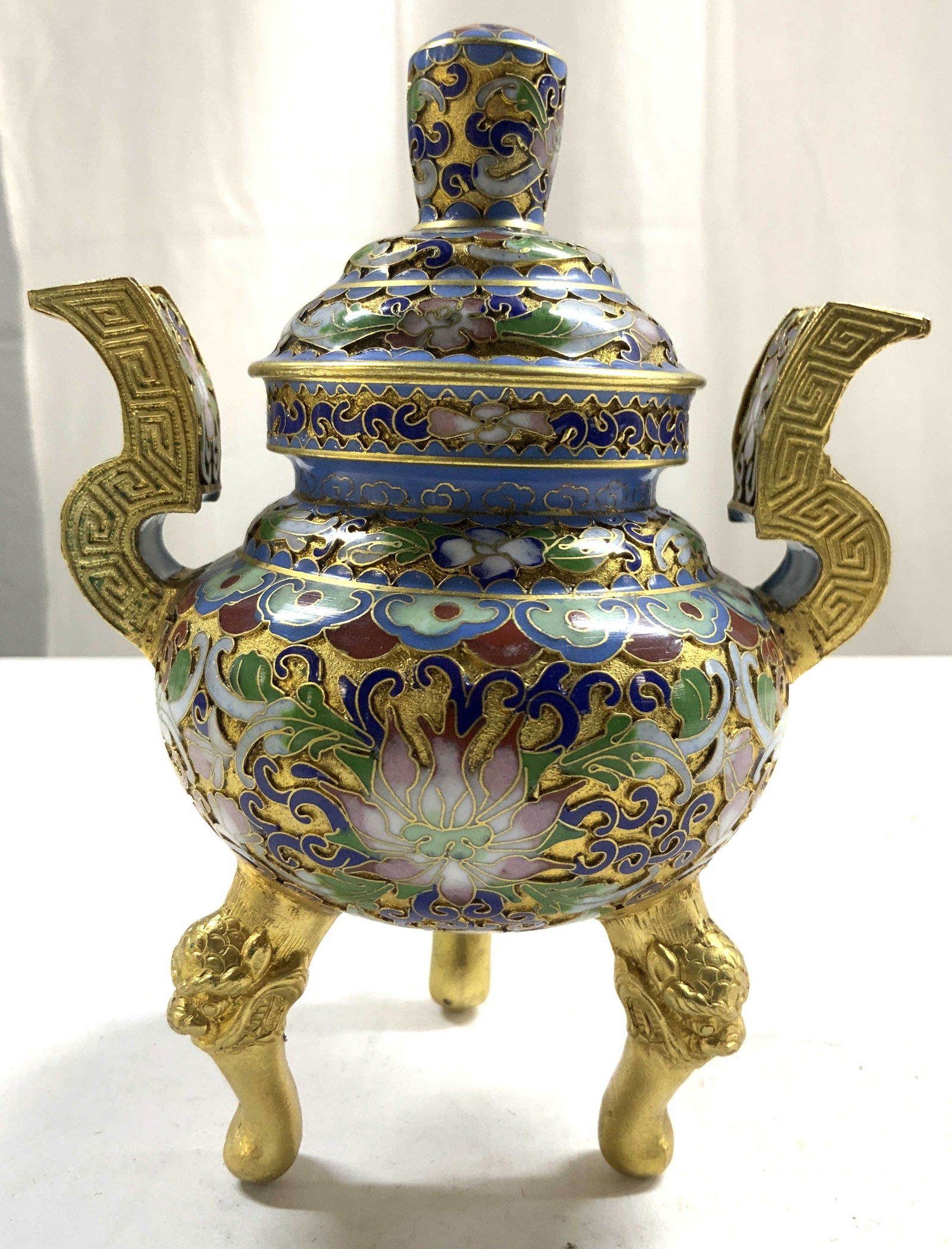 Vintage Chinese Cloisonne Gilt Censer W Lid: Censer is vintage. Cloisonne & gilt center with intricate multi toned floral and leaf enamel detail. Censer has 3 gilt feet with foo dog head detail. Vessel includes lid. Piece has 2 handles. Center m