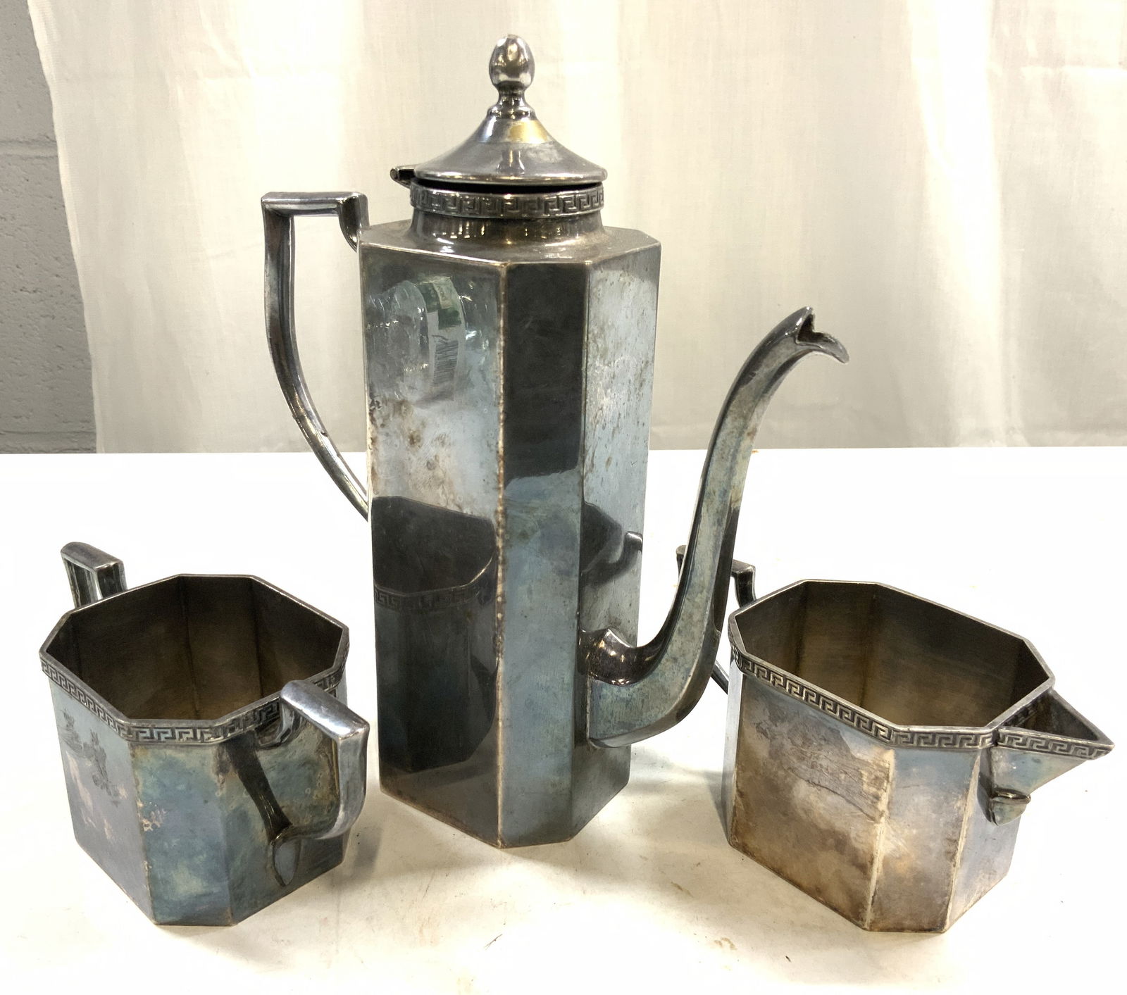 SILO Silver Plated Coffee Pot Creamer & Sugar Dshs: Undersides are inscribed SILO QUADRUPLE SILVER PLATE. Lot includes 1 coffee pot with lid, 1 creamer dish,& 1 sugar dish. Each piece has geometric pattern detailing to rims. Coffee pot measures approxi