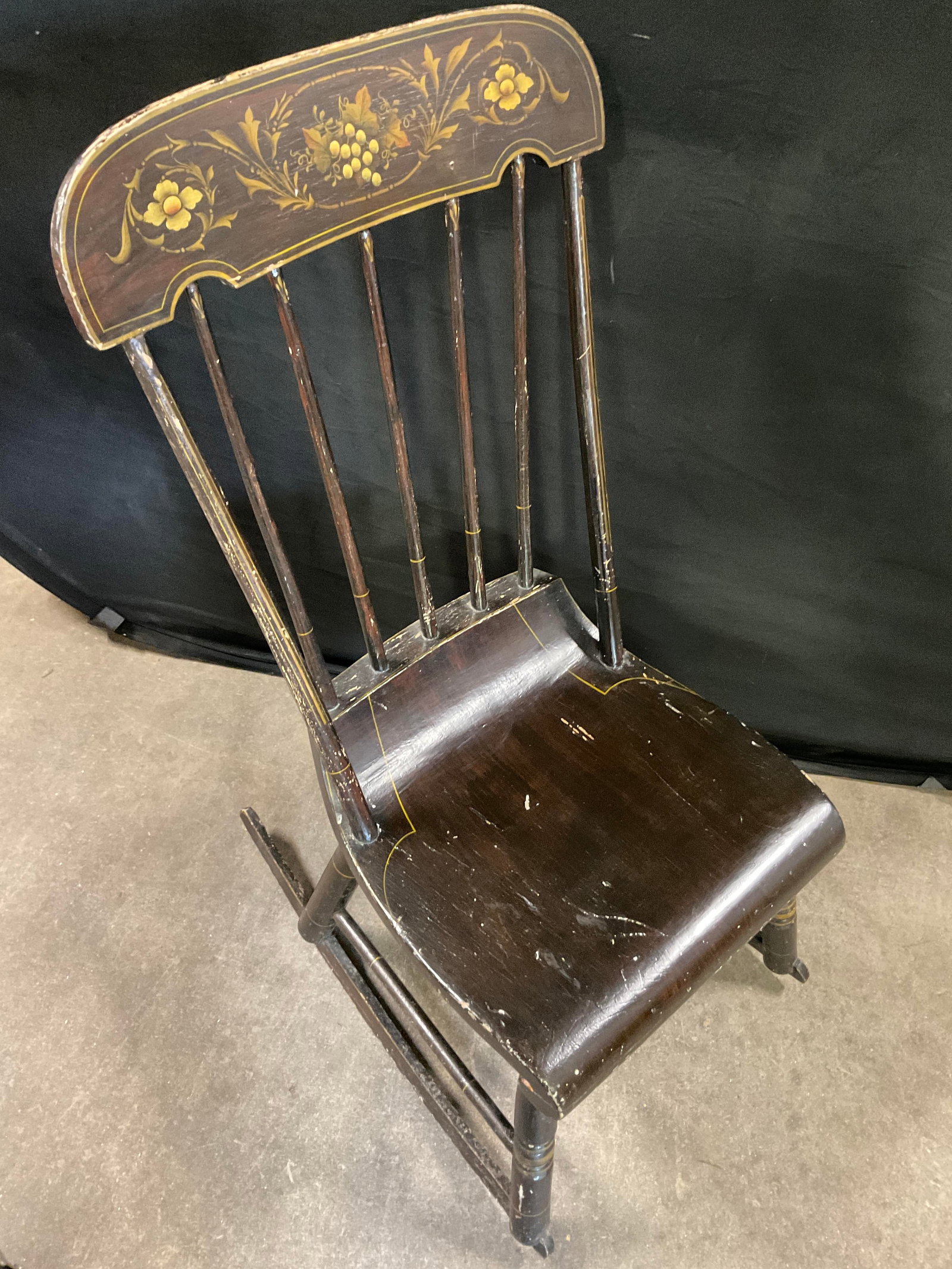 Vtg Stenciled Grapevine Motif Wooden Rocking Chair: Vintage Stenciled Grapevine Motif Wooden Rocking Chair. Deep brown finish to the chair. Spindle backing to the chair. Measures approx. 24D x 15.75W x 36.5H in. Depth measured at base. Chipping, discol