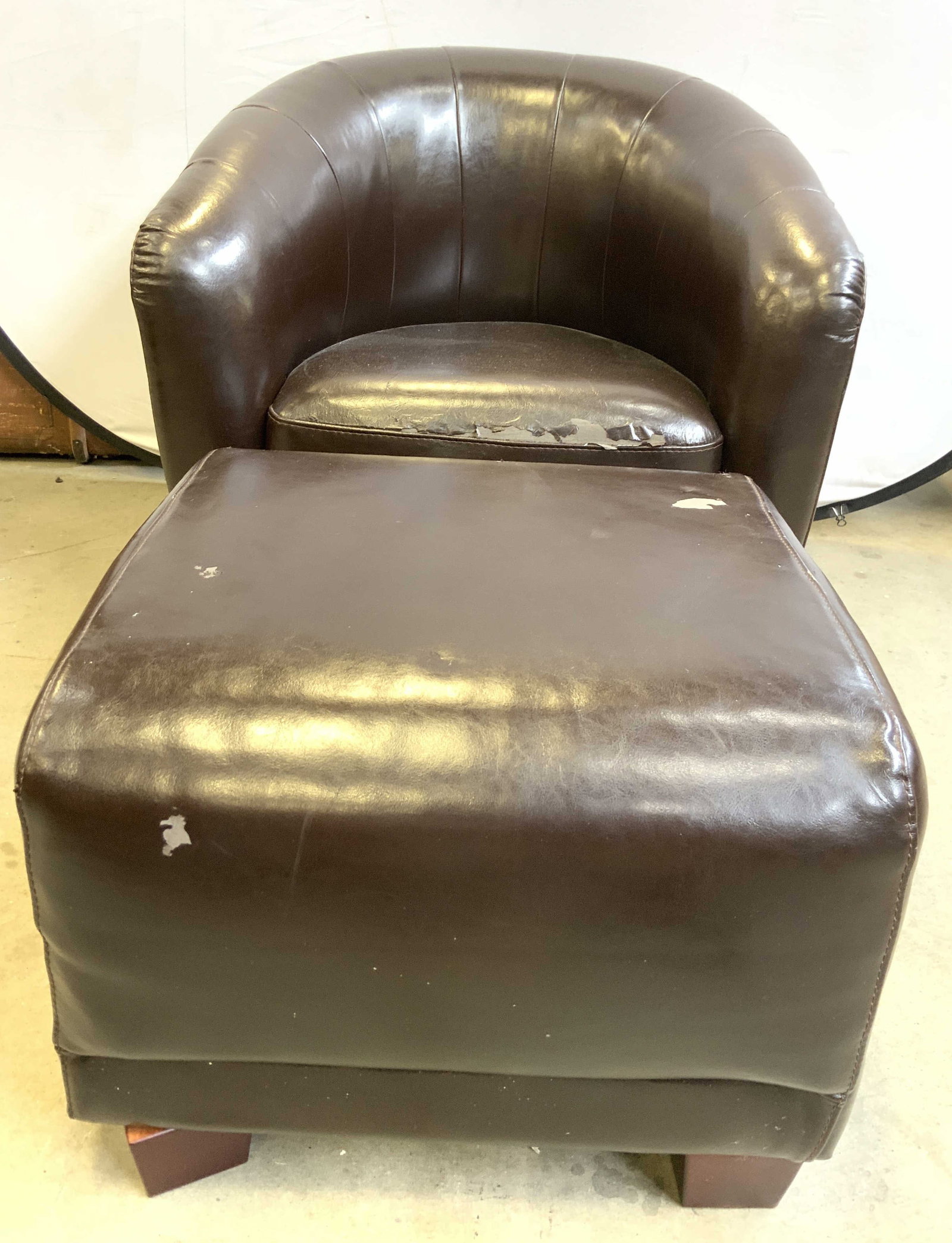 Set Leatherette Upholstered Armchair & Ottoman: Lot includes 1 swivel armchair and 1 ottoman. Each piece is brown toned upholstered with leather style material. Ottoman has wooden feet. Armchair measures approximately 30 inches deep 32 inches wide 