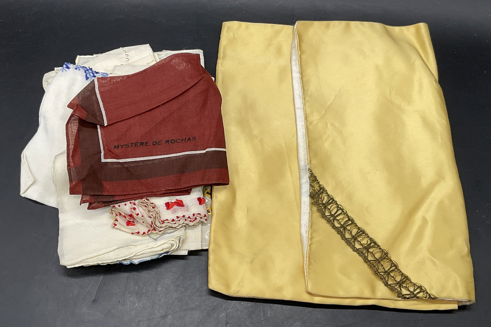 7 Vintage Handkerchiefs & Fabric Pouch, Rochas+: A group lot of seven vintage handkerchiefs and a fabric pouch. The handkerchiefs are a variety of sizes and feature embroidery, patterns, and more. Includes a Mystere De Rochas hankie and others. The