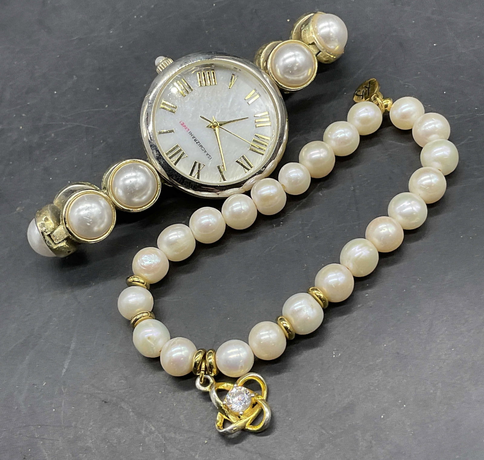 Lot 2 Pearlescent Wrist Watch & Stretch Bracelet: Lot 2 Pearlescent Watch & Stretch Bracelet. The stretch bracelet features a brand trademark charm and a floral charm. The watch features bezel set pearlescent beads. Face reads ISAACMIZRAHI LIVE. Watc