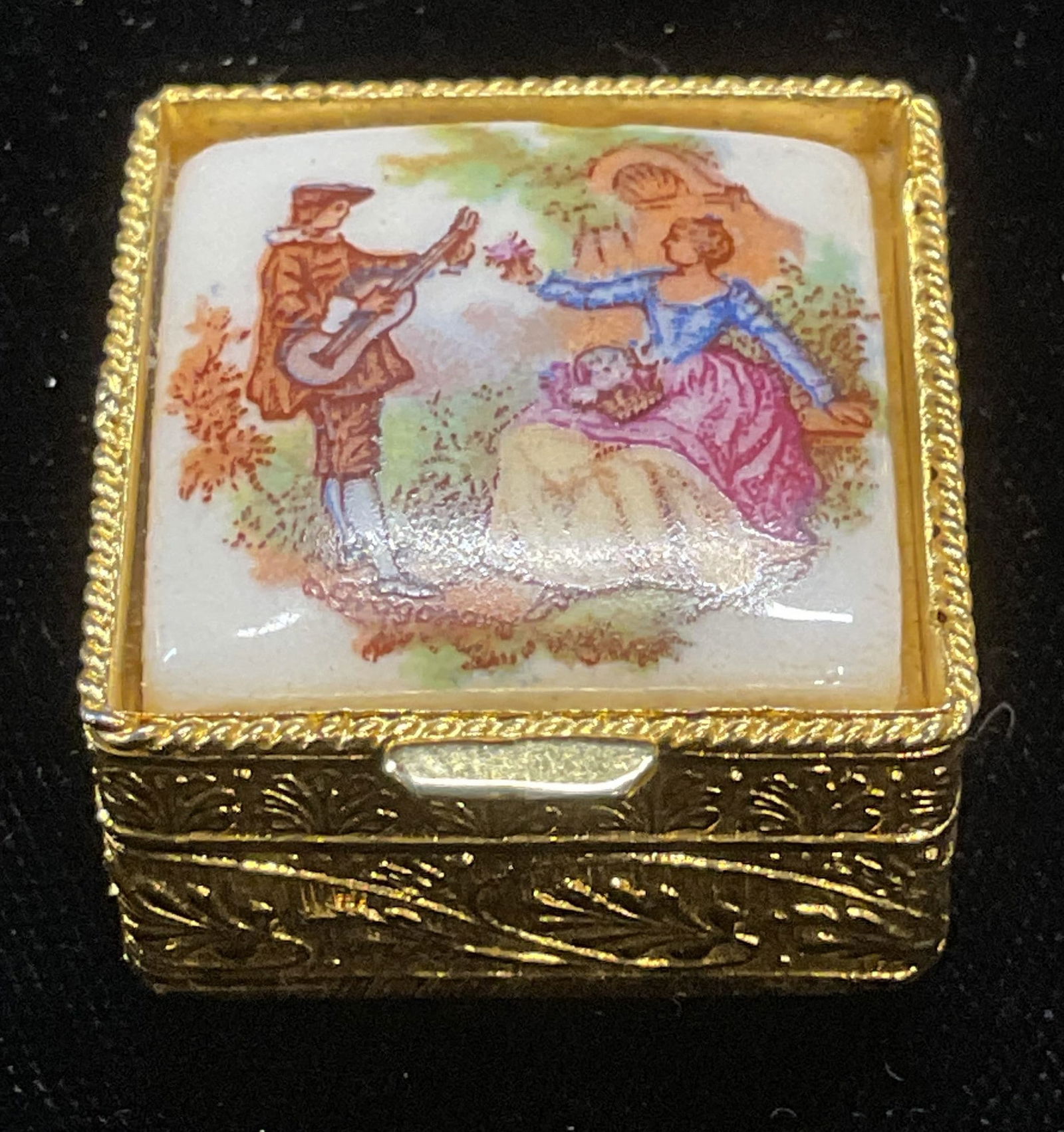 Vtg Gold Tn Porcelain Couple Pill Box: Vintage gold tone pill box with hand painted porcelain decoration. Serenading couple motif. Measures approx 1 x 1 x 5/8 inches. Some wear consistent with exposure. Inventory from Manhattan jewelry sto