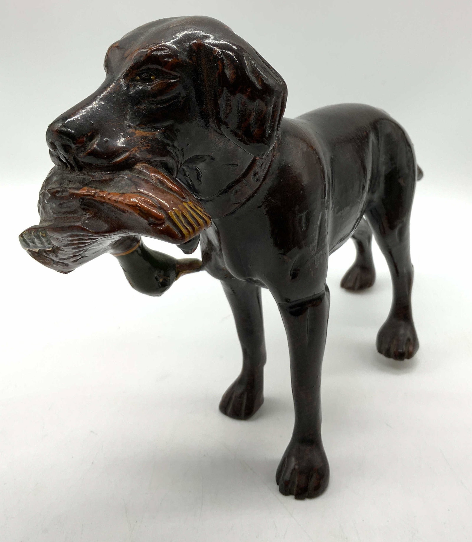 Wooden Hunting Dog Figurine W Goose in Mouth: Wooden Hunting Dog Figurine W Goose in Mouth Figurine depicting a hunting dog in a standing pose with a bird in its mouth. No visible signatures or markings. Surface wear consistent to age, use & expo