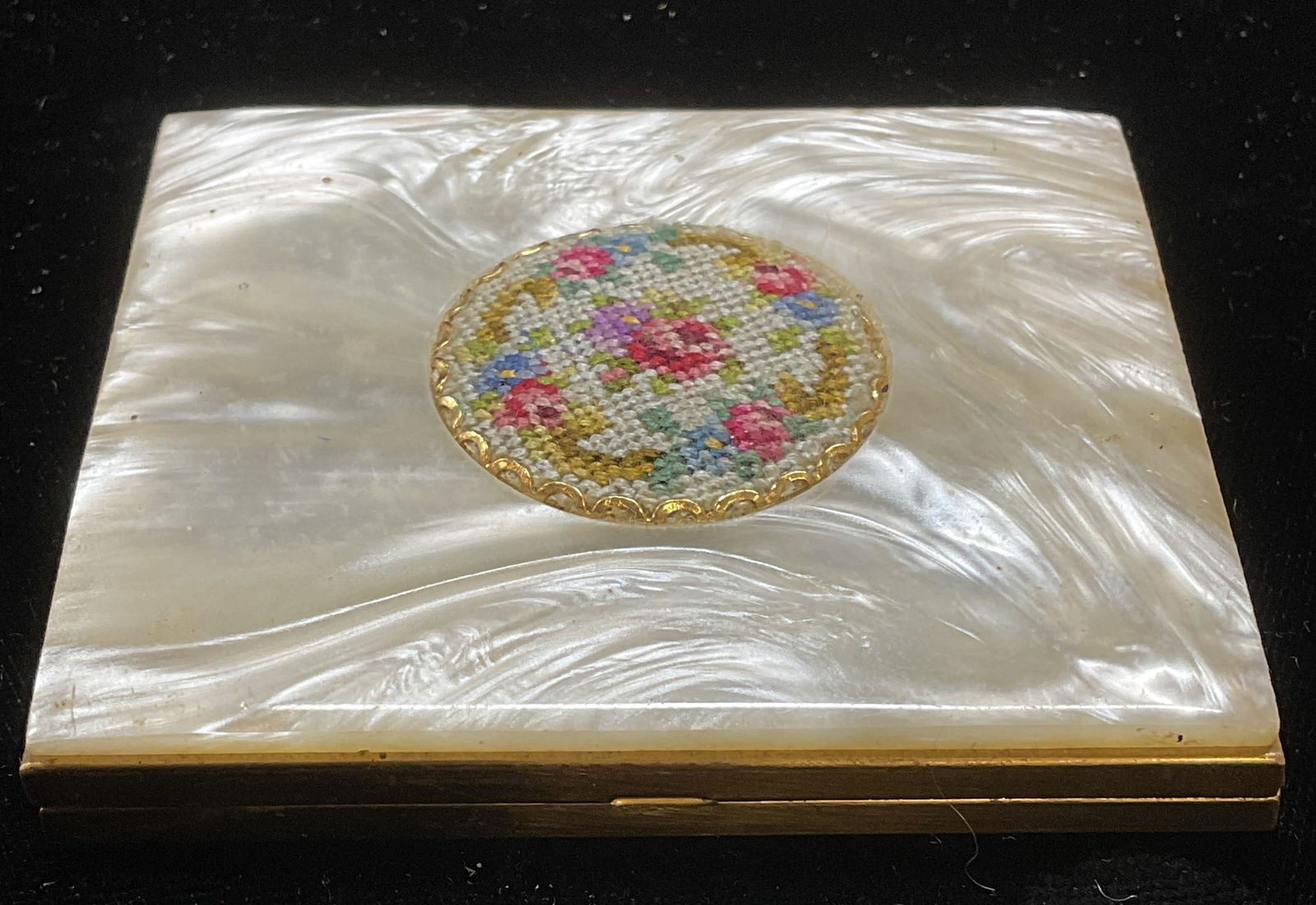 Vintage Gold Tn Faux MOP Needlepoint Hand Mirror: Vintage gold tone hand mirror with faux mother of pearl outer decoration and needlepoint floral motif. Measures approx 2.75 x 2.5 x 3/8 inches. Some wear consistent with exposure. Inventory from Manha