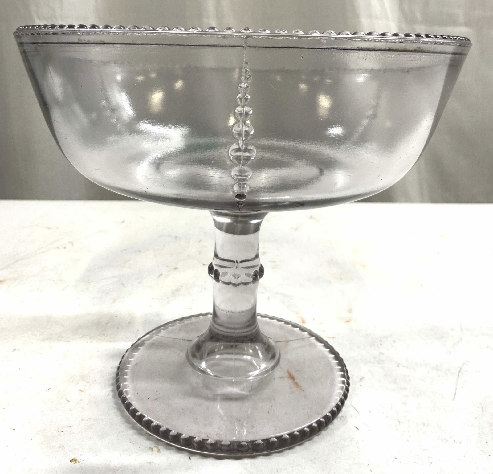 D.C. Jenkins Kokomo Bead Column Gls Compote: Compote appears to be DC JENKINS GLASS.(no apparent markings). Compote has subtle smoky purple tone. Rim and & base have beaded detail. Compote is glass. Piece measures approximately 6.25 inches tall