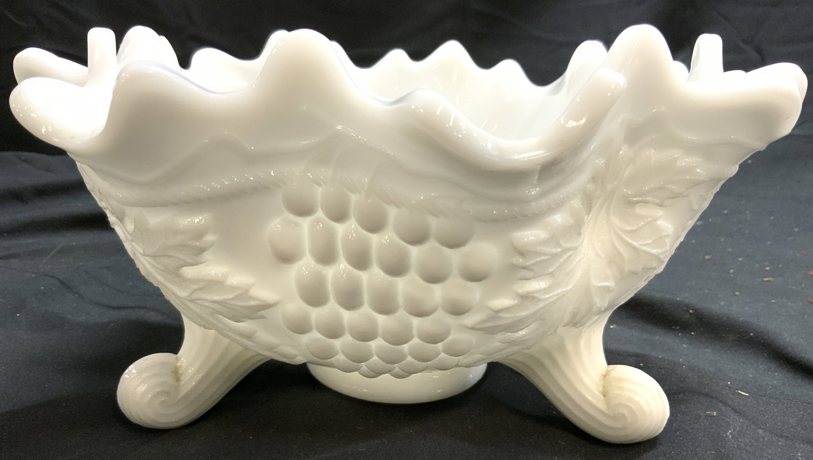 Vtg Footed Milk Glass Bowl W Grape & Leaf Detail: Bowl is white toned and glass with intricate grape and leaf detail to exterior. Bowl has 3 curled feet. Vessel is vintage. Footed milk glass bowl with grape and leaf detail. Measures approximately 10.