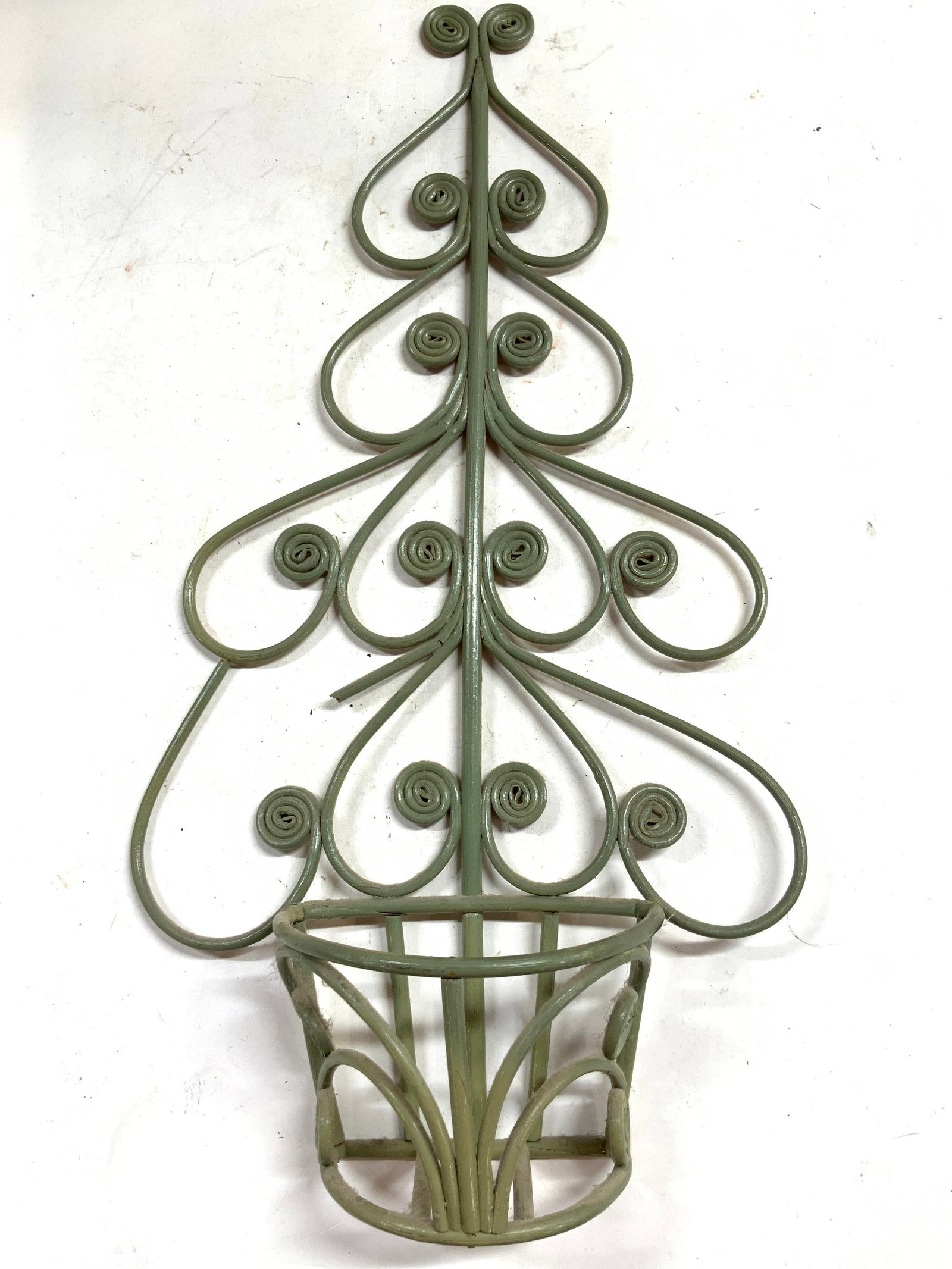 Vintage Rattan Wall Planter Holder: Planter holder is Vintage. Piece is rattan & painted green toned. Piece has planter holding area at base. Numerous curled structures. Piece measures approximately 22 inches tall 11.5 inches wide 4 inc