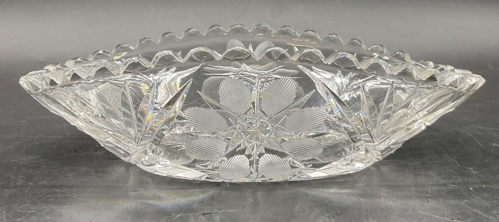 Vintage Cut Glass Sawtooth Rim Trinket Dish: Vintage Cut Glass Trinket Dish. Cut floral and starburst motifs throughout. Sawtooth rim to the piece. Measures approx. 2H x 7W in. Discoloration, surface wear, and chipping present. home decor, home 