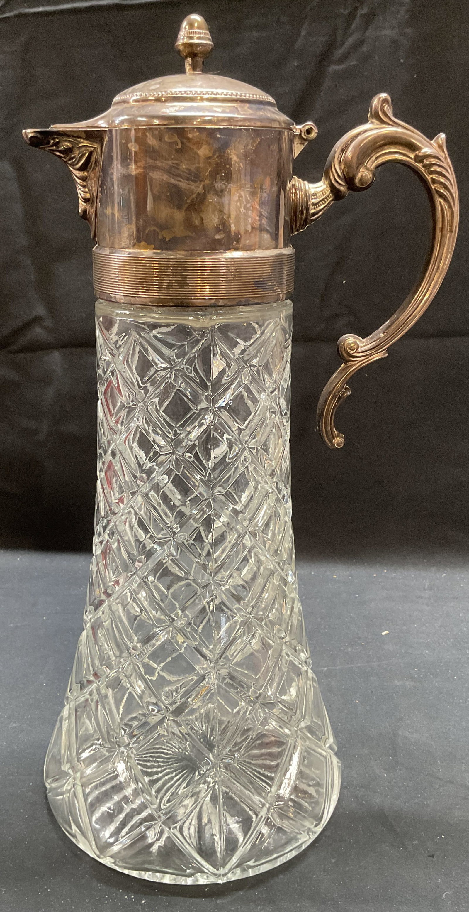 Vintage Silver Plated Crystal Wine Pitcher: Vintage crystal wine or water pitcher with silver plated lid and handle. Diamond pattern and raised scroll handle. Measures approx 5.75 x 14 inches. Piece had weight. As Is, lid hinge needs repair. Su