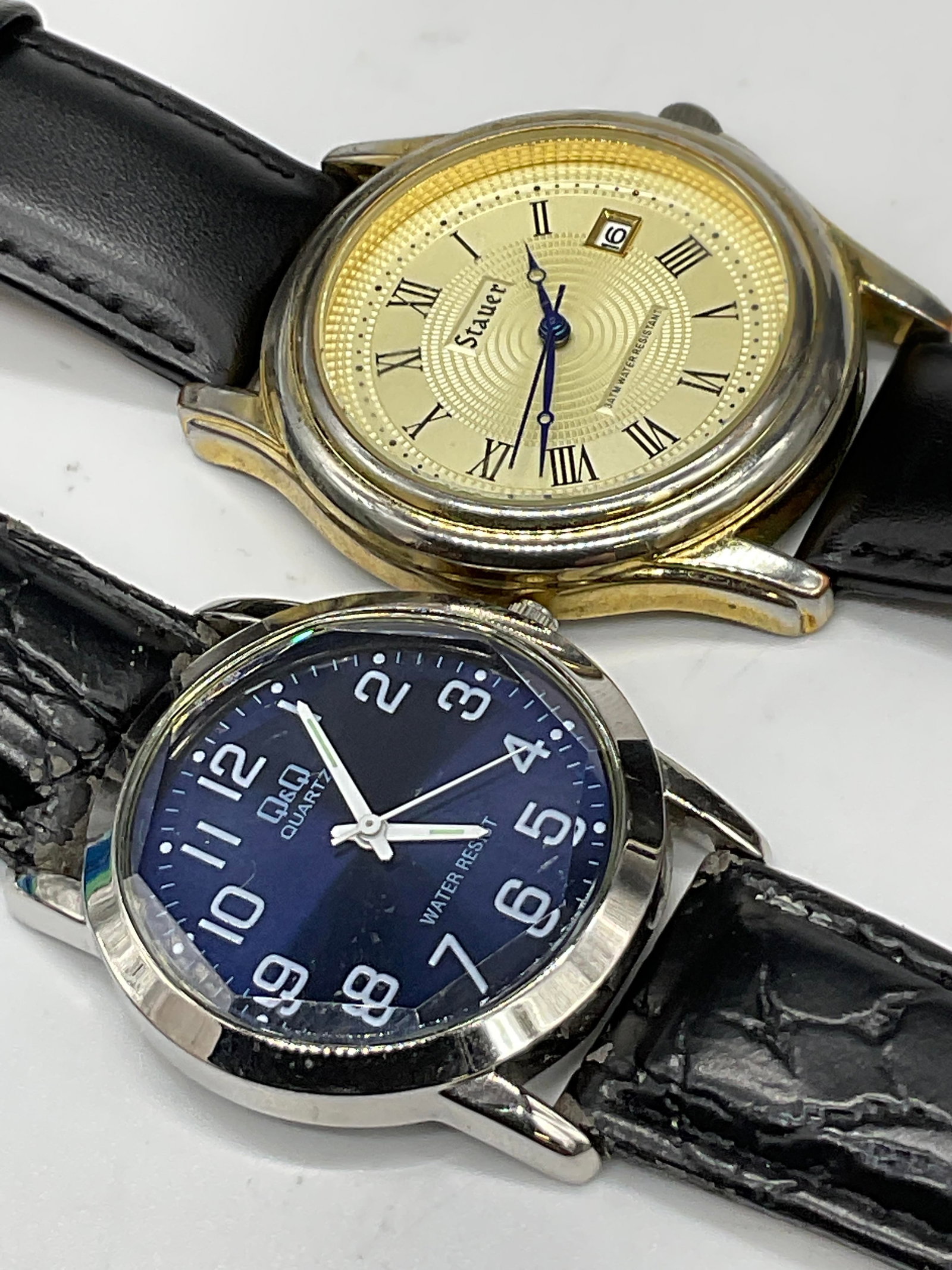 Lot 2 STAUER & Q&Q Black Band Wristwatches: Lot of Two STAUER & Q&Q Black Band Wristwatches. One reads Q&Q QUARTZ, the wristband appears to be crafted from leather style material. The other reads STAUER and the wristband reads Genuine Calf Skin