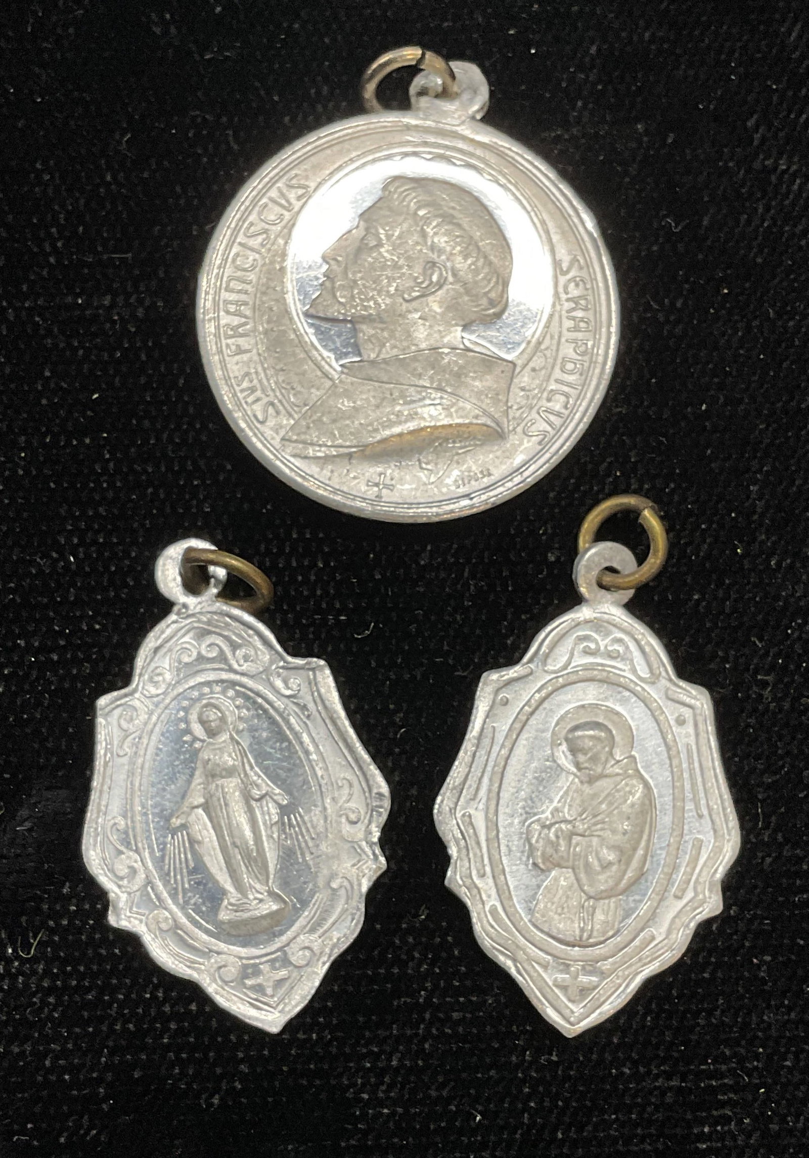Lot 3 Religious St Francis, Mary Pendants: Lot of 3 silver tone religious Catholic motif pendants with St Francis and Mary motifs. Largest measures approx 7/8 inches wide. Some wear including scratching observed. Jewelry, estate jewelry, costu