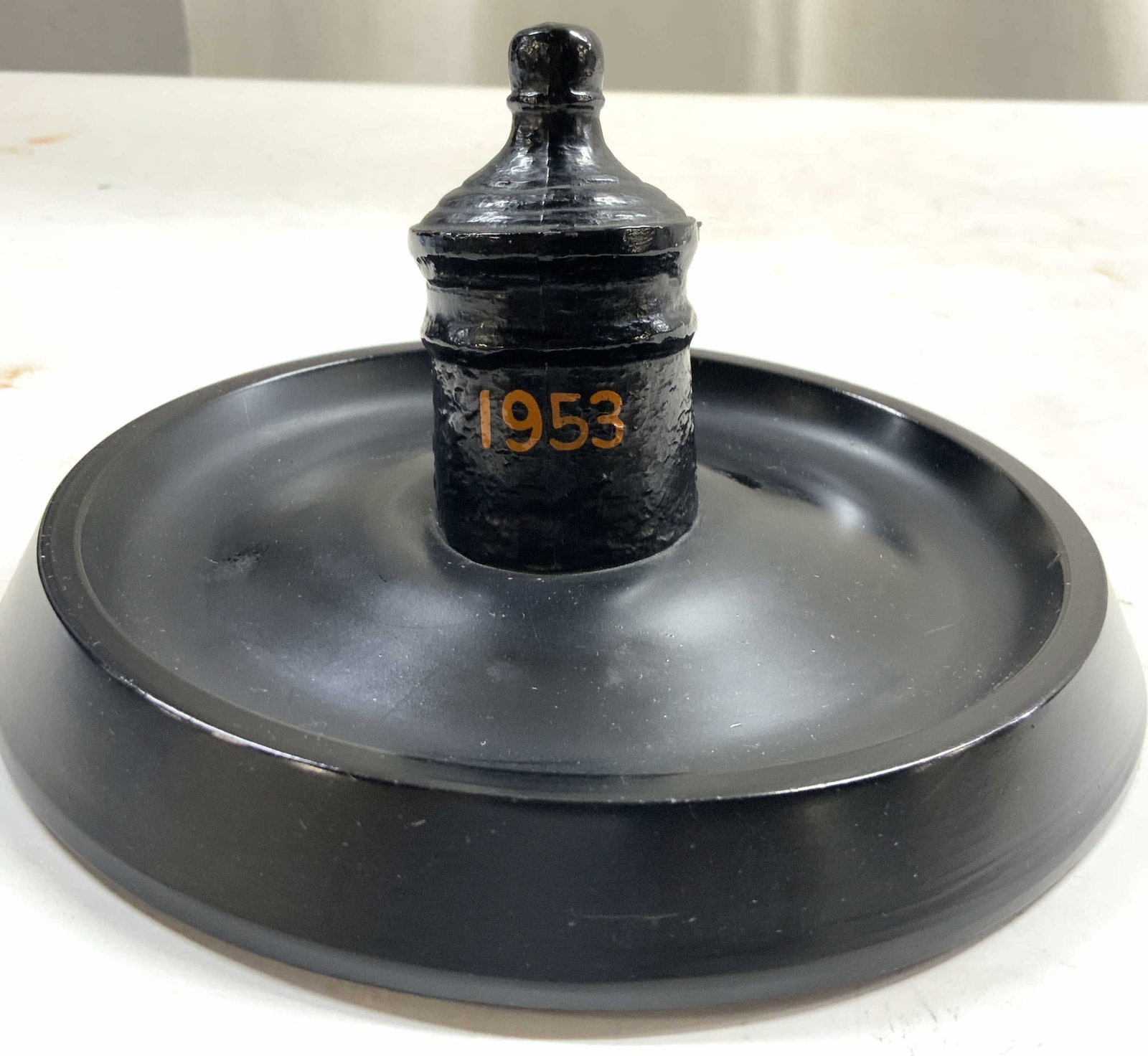 Vintage Composite Paperweight Blk 1953: Monogrammed FOR SERVICE TO PRINCETON. Paperweight is black toned and Vintage. Piece has orange toned year marked 1953. Object is crafted from heavyweight composite material. Piece has circular vase. U