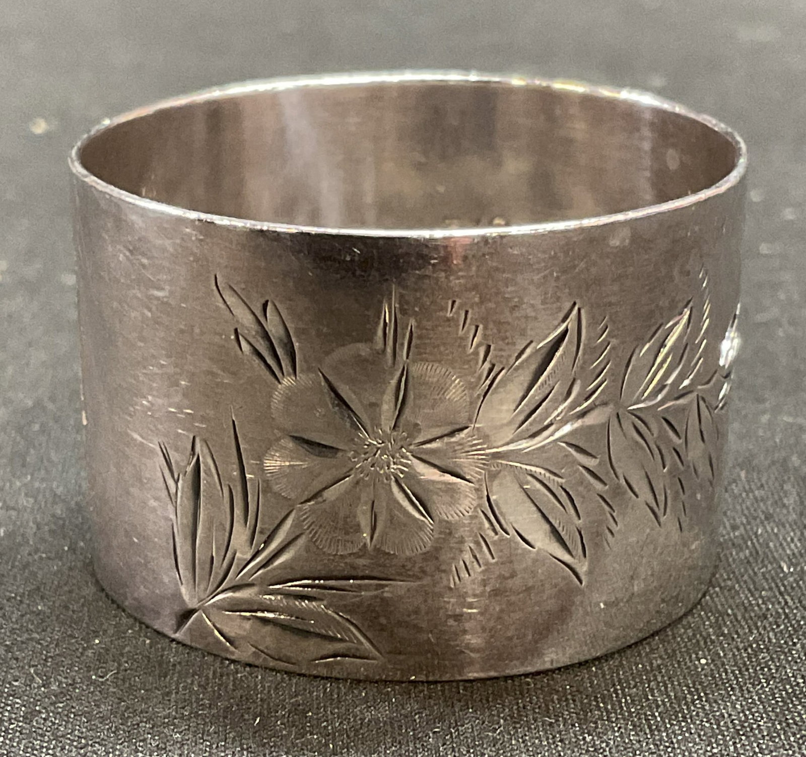 Signed Sterling Silver Floral Butterly Napkin Ring: Signed Sterling silver napkin ring. Engraved floral and butterfly motif. Signed with hallmarks. Marked sterling. Measures approx 1.5 x 1 inches. Total weight .74 ozt. Some scratching observed. Sterlin