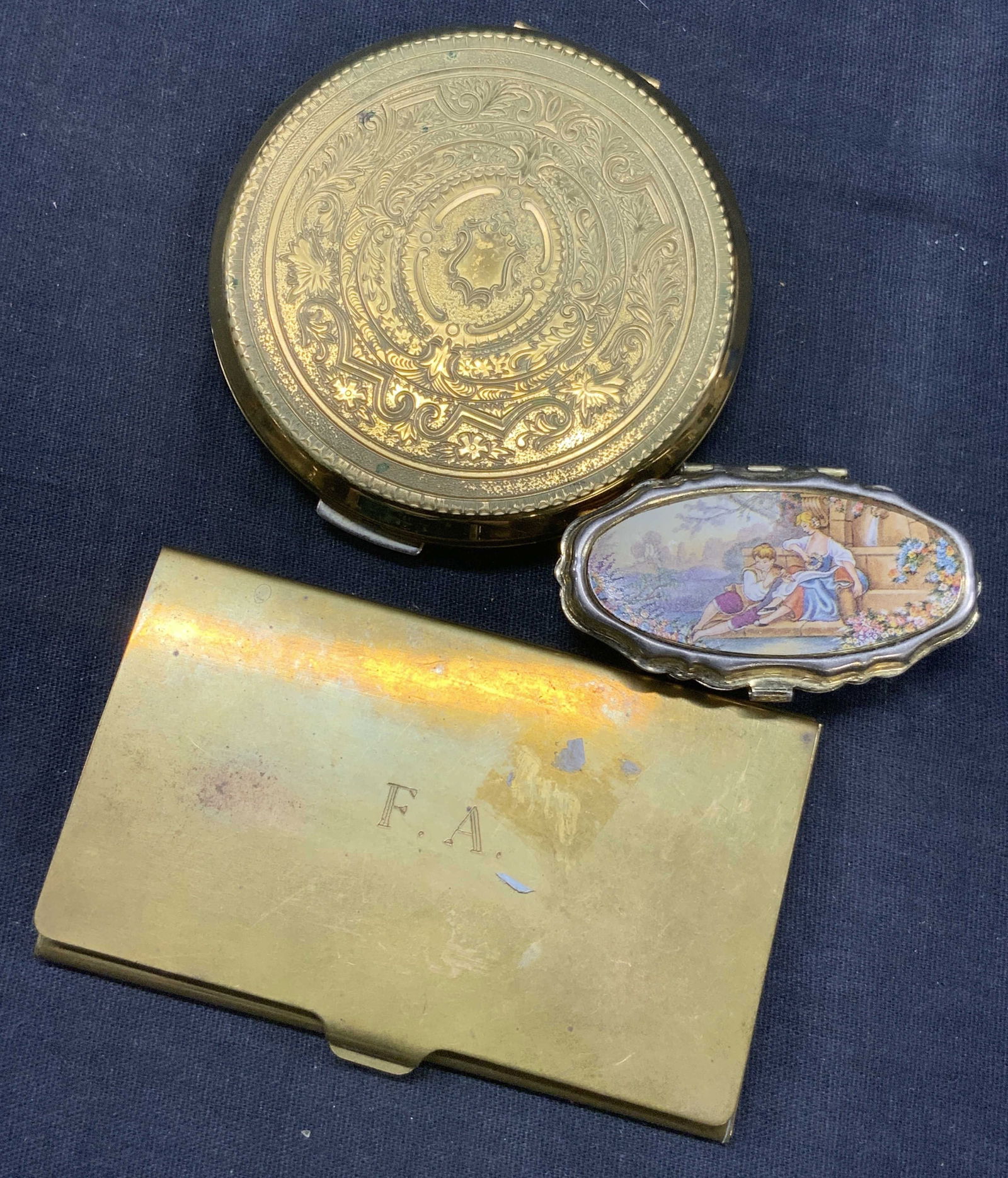 Lot 3 Vtg Etched Brass Pill Boxes & Card Holder: Lot of 3 Vtg brass accessories, 2 brass pill boxes, 1 with a litho of classical figures on the lid, and the other with intricate etchings on lid in scroll patterns with floral accents and possibly Bak