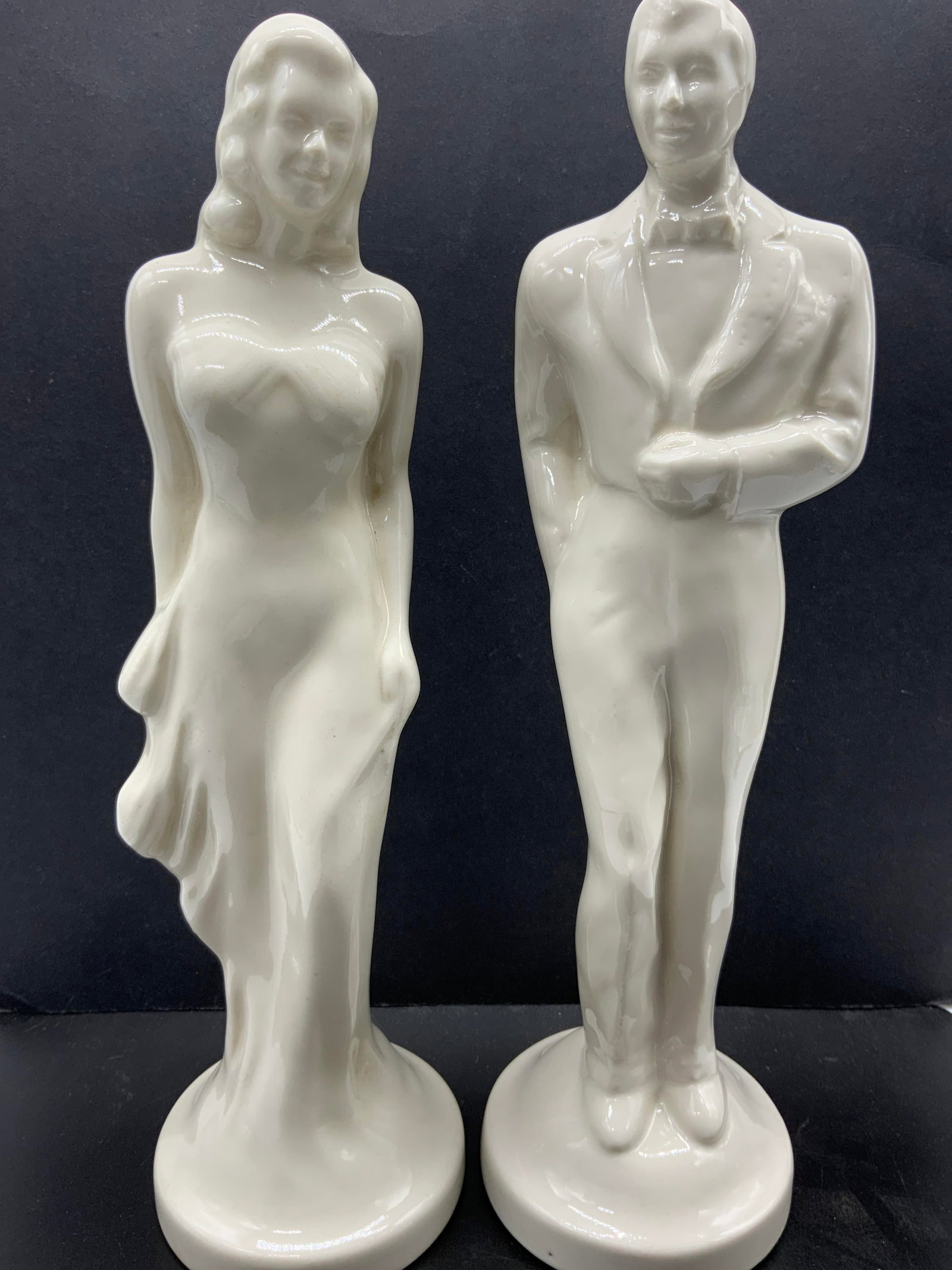 Pair Bride & Groom Wedding Porcelain Figurines: Art deco Bride & Groom Wedding Porcelain Figurines Porcelain figurines depicting a bride & groom in a standing pose. They appear to be smiling. Surface wear consistent to age, use & exposure. Measurem