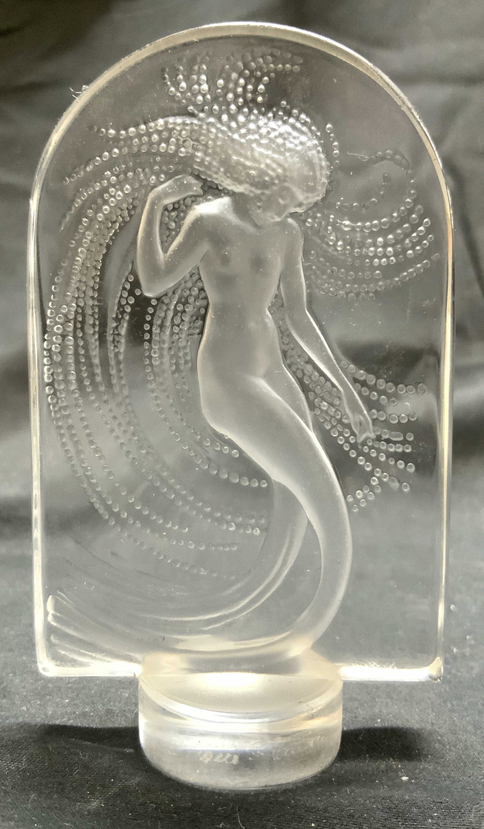LALIQUE FRANCE Fem Nude Crystal Nymph Relief: Base is signed LALIQUE FRANCE. Relief depicts a female nude nymph figure in frosted detail. Top of piece has arch form. Base has circular form. Relief is crystal. Piece measures approximately 3.75 inc