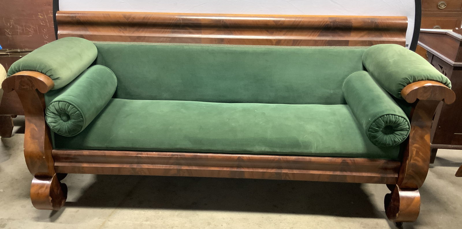Vtg Uph Empire Wooden Box Sofa On Casters: Sofa is vintage & wooden. Piece has green toned Upholstery. Empire sofa sits on gilt metal casters. Lot includes 2 cylindrical bolster pillows. Sofa has carved wooden feet. Measures approximately 76 i