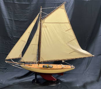 Bermuda Sloop Scale Model Sailboat On Stand 34in H: Sailboat scale model depicts a Bermuda Sloop/ pond yacht. Piece has tan , maroon and cream tones. Lot includes black toned stand. Piece has tan toned sails. Scale model appears to be wooden. Measures