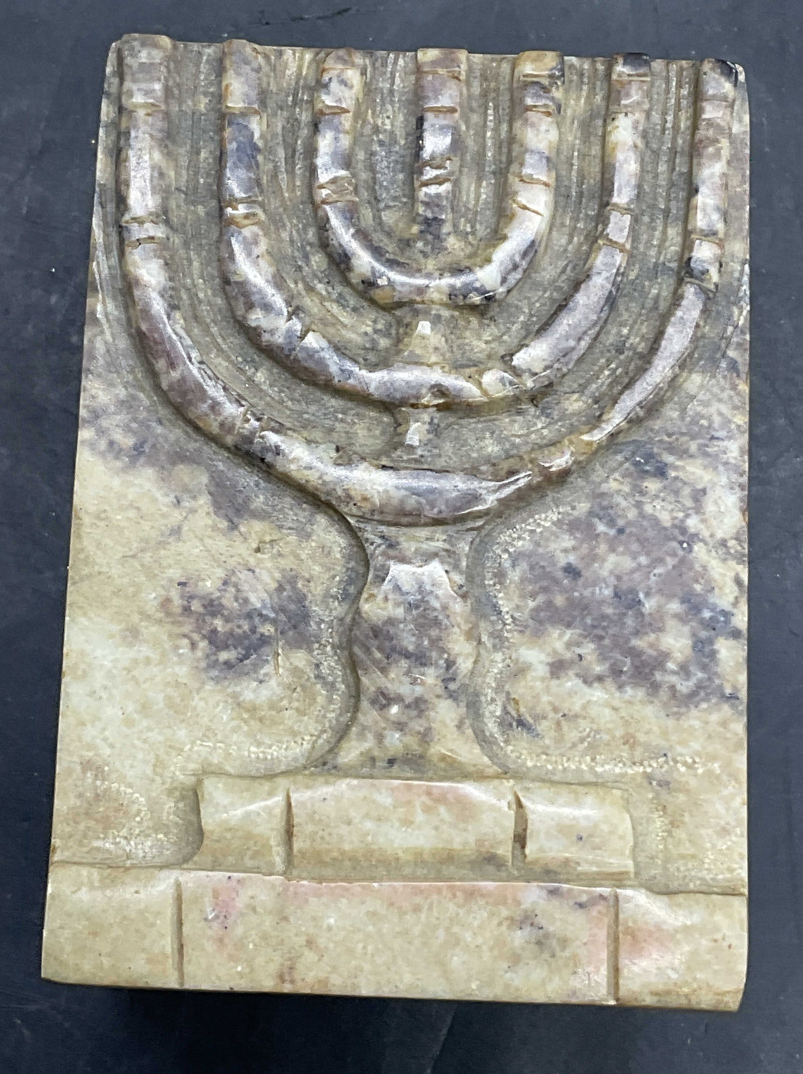 JERUSALEM STONE Menorah Motif Trinket Box, Lid: JERUSALEM STONE Menorah Motif Trinket Box. Raised menorah to the lid. Pierced stonework to the box. Measures approx. 1.25H x 3W in. Measured at widest point. Sticker to underside reads JERUSALEM STONE