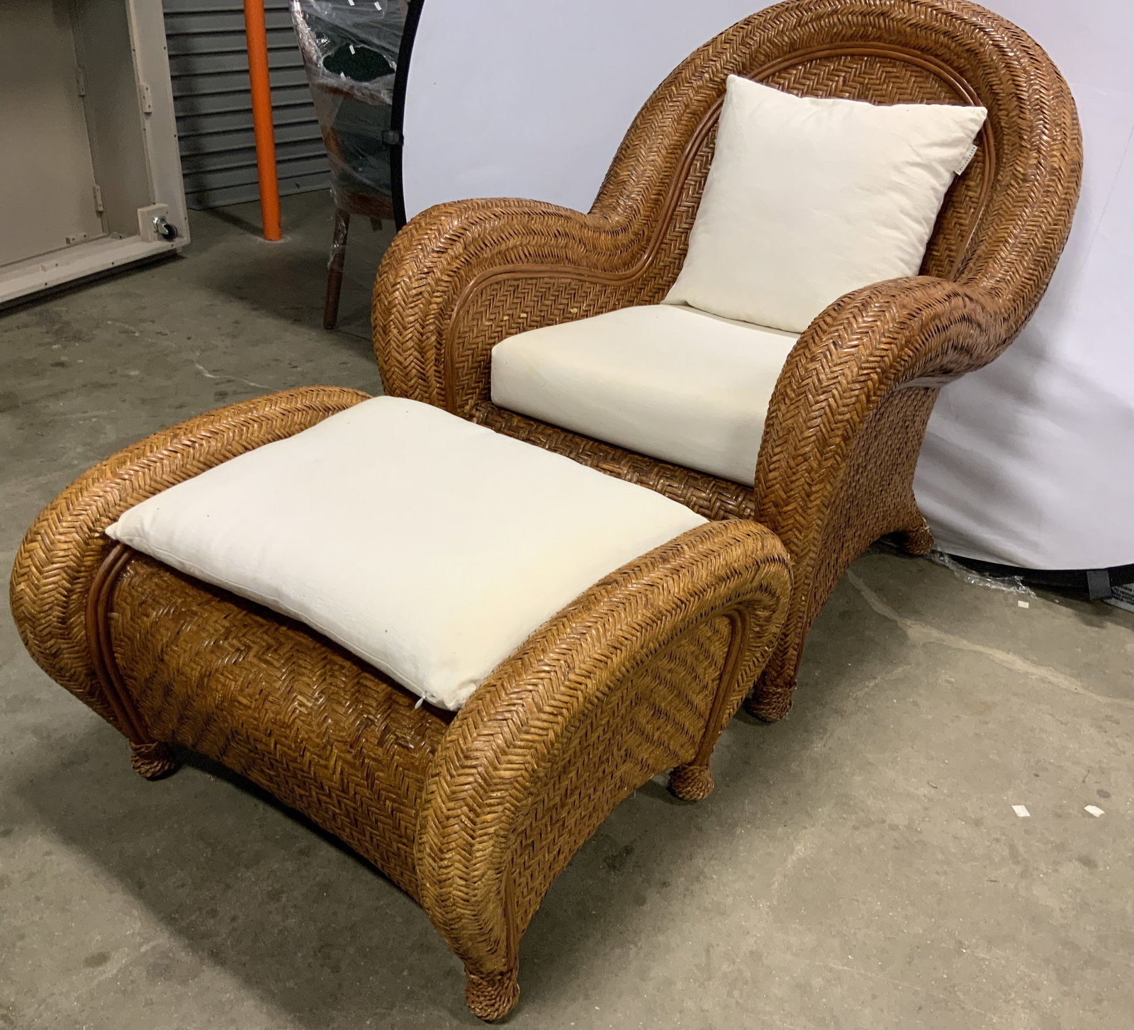 Vntg Rattan Armchair & Ottoman W Cushions: Lot includes 1 armchair and 1 matching ottoman. Chair and ottoman are both tan toned woven rattan. Each piece includes cream toned cushions. Armchair measures approximately 38 inches tall & deep 31 in
