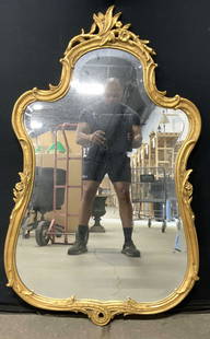 Vintage Beveled Ornate Gilt Wood Wall Mirror 46in: Mirror has gilt wood frame. Mirrored surface is beveled. Piece has ornate scroll, floral and leaf detail. Mirror is vintage. Mirror measures approximately 46 inches tall 27 inches wide. Mirror, wall m