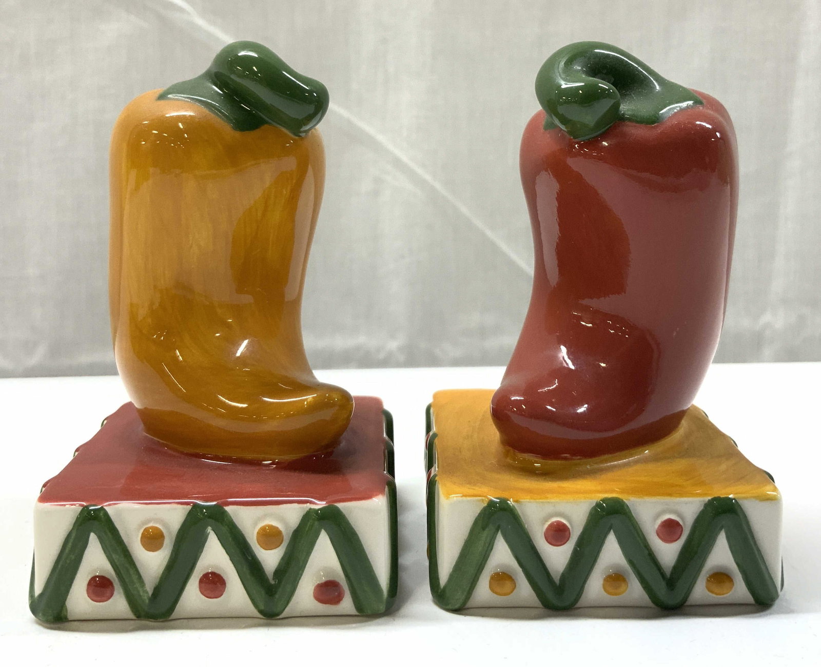 CLAY ART Chili Peppers Ceramic S&P Shakers: CLAY ART Chili Peppers Ceramic S&P Shakers Ceramic salt & pepper shakers depicting red & yellow chili peppers. Peppers are on a colorful southwestern style base with zigzag lines. Signed & marked on u
