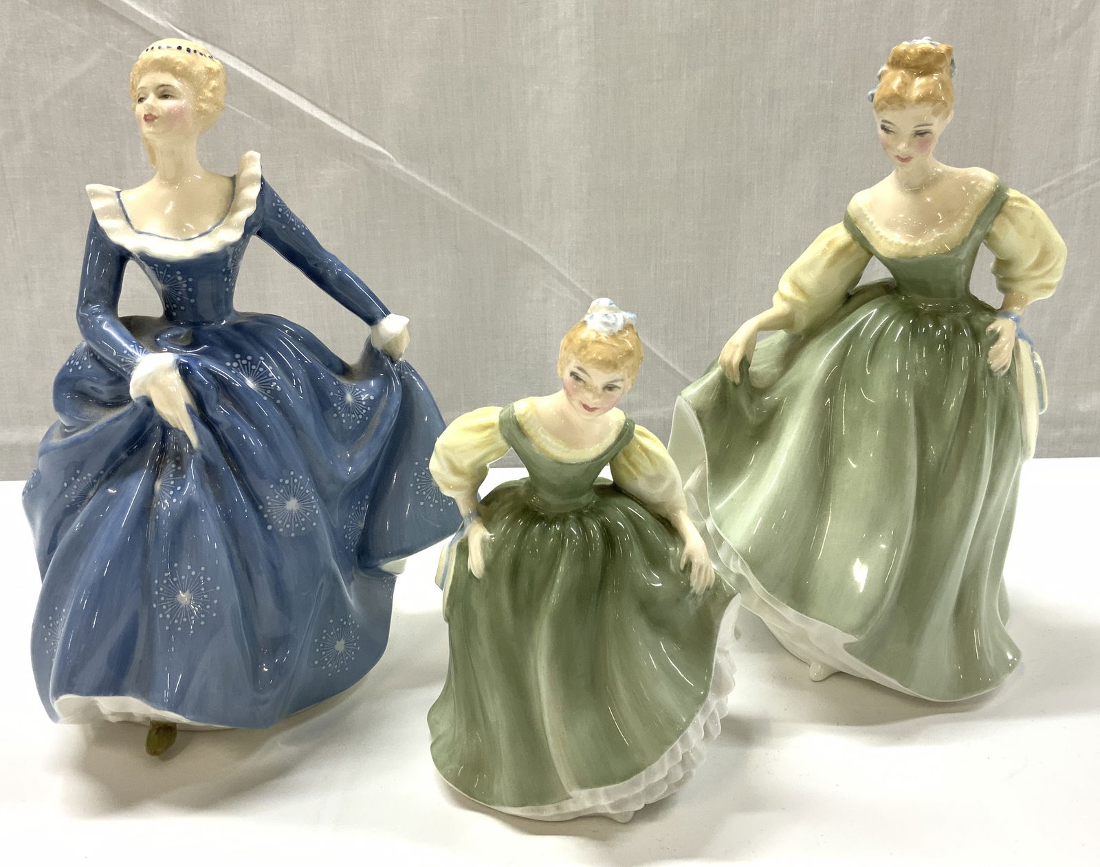 3 ROYAL DOULTON Fair Maiden Figurines ENGLAND: 3 ROYAL DOULTON Fair Maiden Figurines ENGLAND 3 bone china figurines including, fair lady, fair maiden & fragrance lady. Figurines are wearing a green or blue dress adorned with a snowflake pattern &