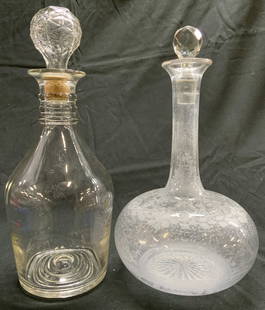 Lot 2 Art Glass Decanters W Stoppers: Lot includes 2 decanters. Each are glass. Decanters each include stoppers. One Decanter has frosted floral and leaf detailing. Underside of one reads LP 5700 65 55 D 10 7. Larger decanter measures app