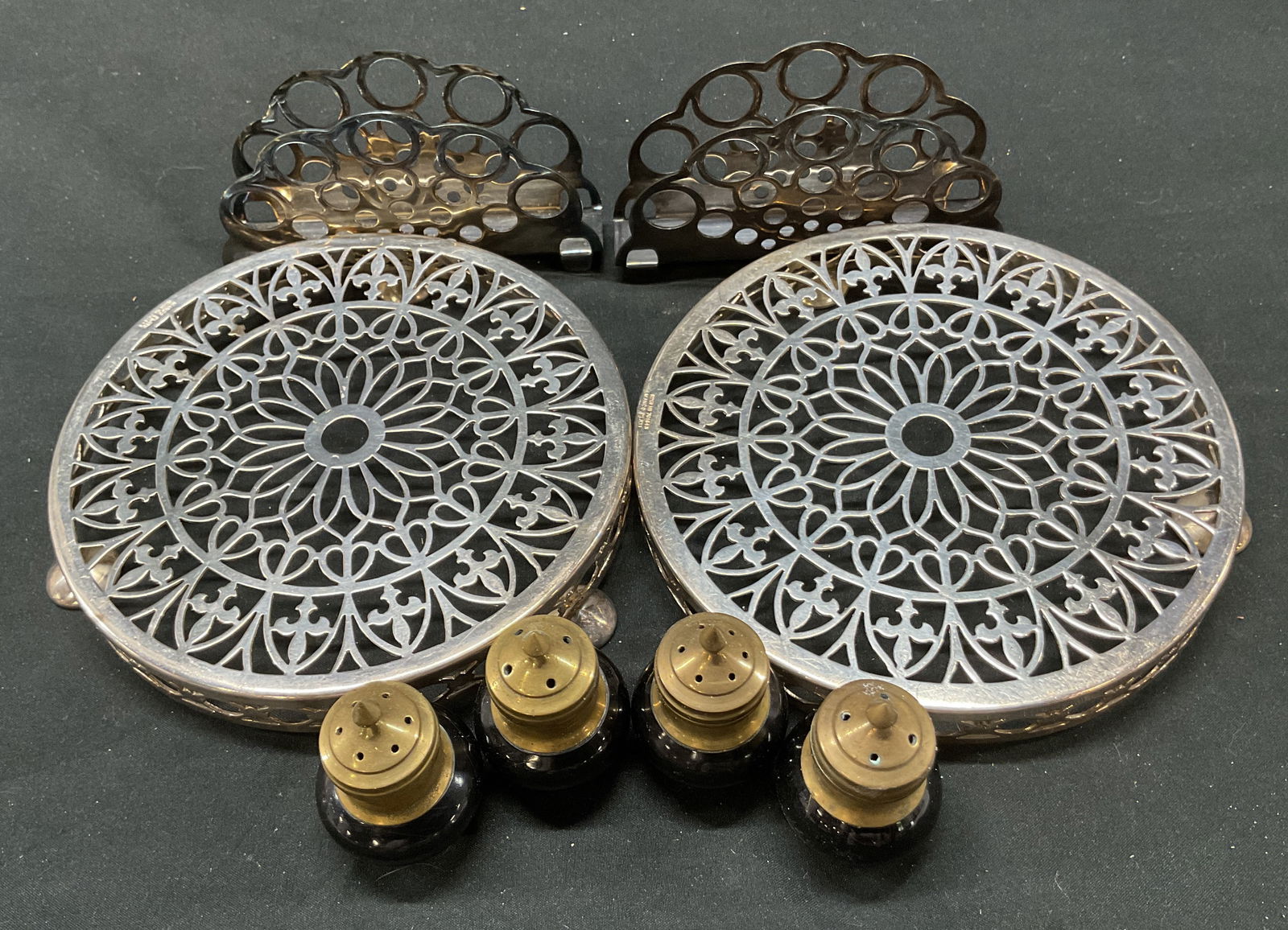 Grp 8 Silver Plt Trivet, Napkin Holders, Shakers: Group lot 8. Includes 2 Manco Electroplate trivets, 2 Hefra napkins holders, 4 salt and pepper shakers. 6 x 1 inches. Some surface wear including scratching. Different Metals in group including silver