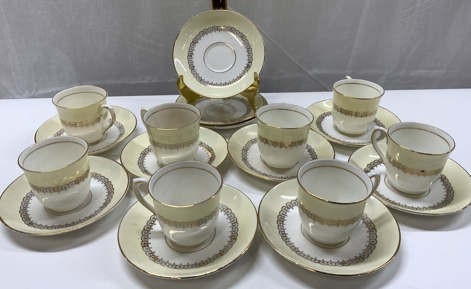 20 COLCLOUGH Bone China Saucer & Teacup Set ENGLAND: 20 COLCLOUGH Bone China Saucer & Teacup Set ENGLAND 11 saucer plates & 9 teacups. Each piece has an outer yellow band & a white center with intricate gold detailing & a gold rim. Underside is signed &