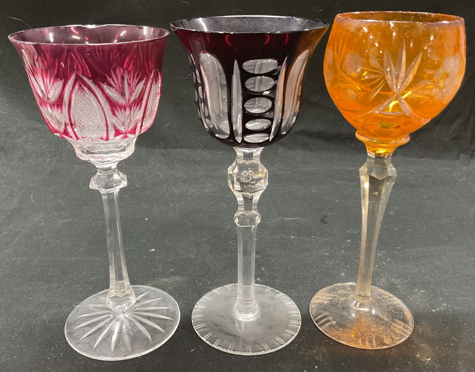 Lot 3 Colorful Cut Wine Glass Goblets: Lot 3 colorful cut wine glasses. Lot includes 1 deep red geometric pattern, 1 pink floral pattern, 1 orange floral pattern. 8.25 x 3.75 inches. Some surface wear consistent with exposure. Slight scrat