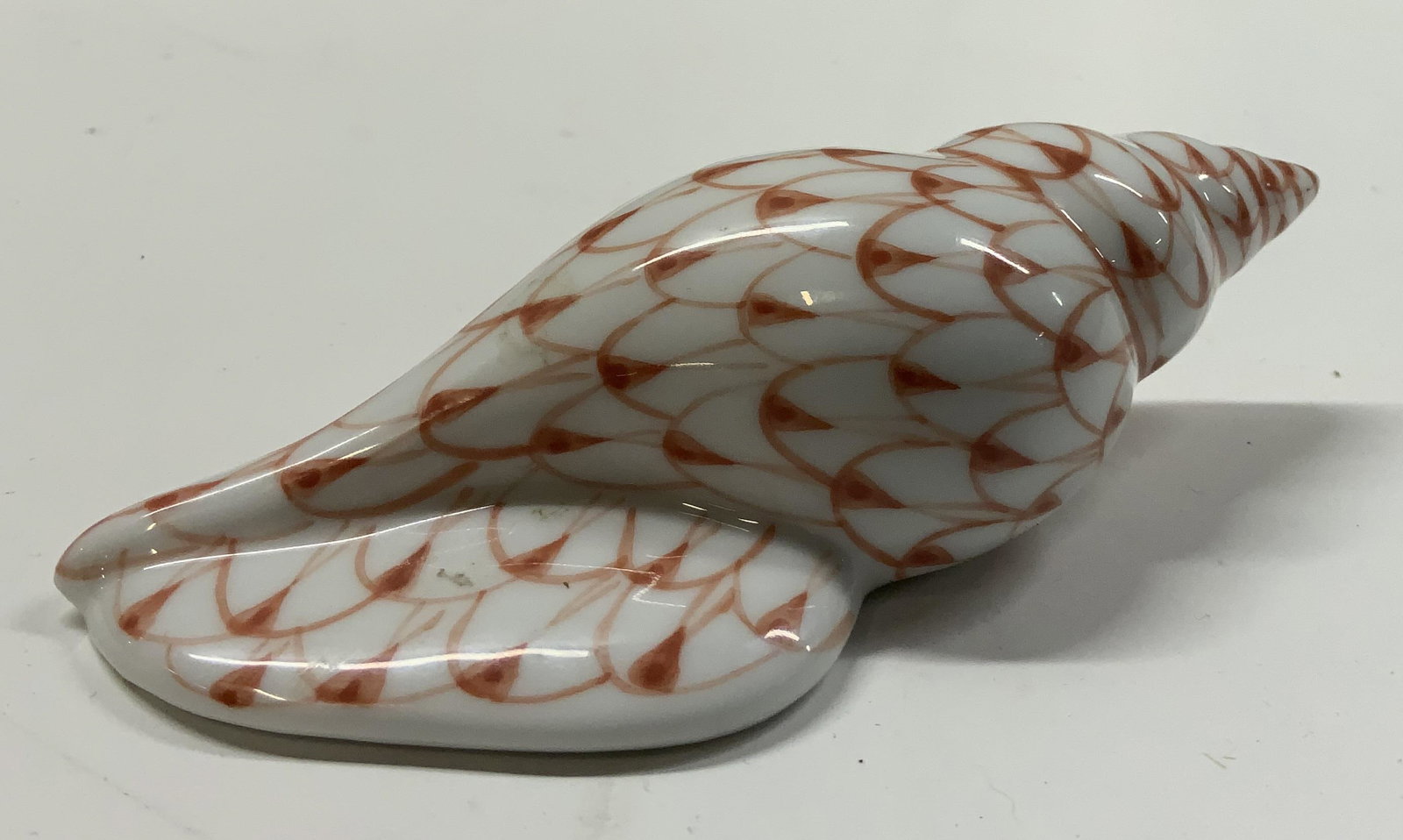 Andrea by Sadek Porcelain Sea Snail Shell Figurine: Andrea by Sadek Porcelain Sea Snail Shell Figurine. Shell porcelain figure, has a white base with orange/reddish colors. Has a shell pattern on the figurine. Underside reads Andrea by Sadek. Made in T