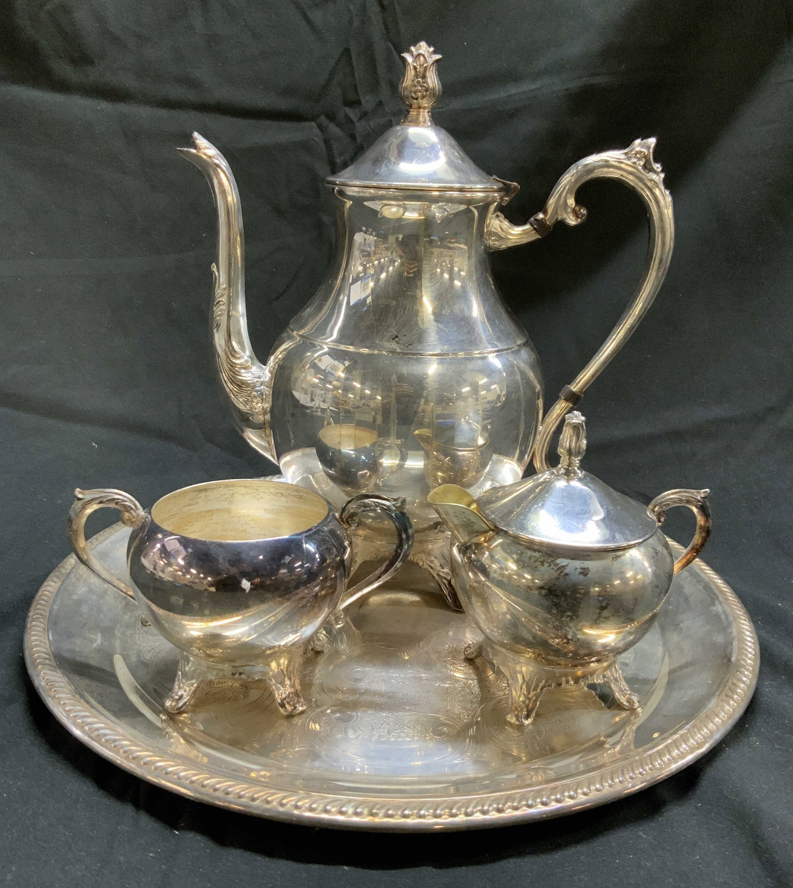 FB RODGERS Set 4 Silv Pl Tea Service: Underside of each piece is inscribed FB RODGERS. Lot includes 1 serving dish, 1 creamer dish with lid, 1 teapot with lid & 1 sugar dish. Serving tray has circular form. Piece has Intricately etched fl