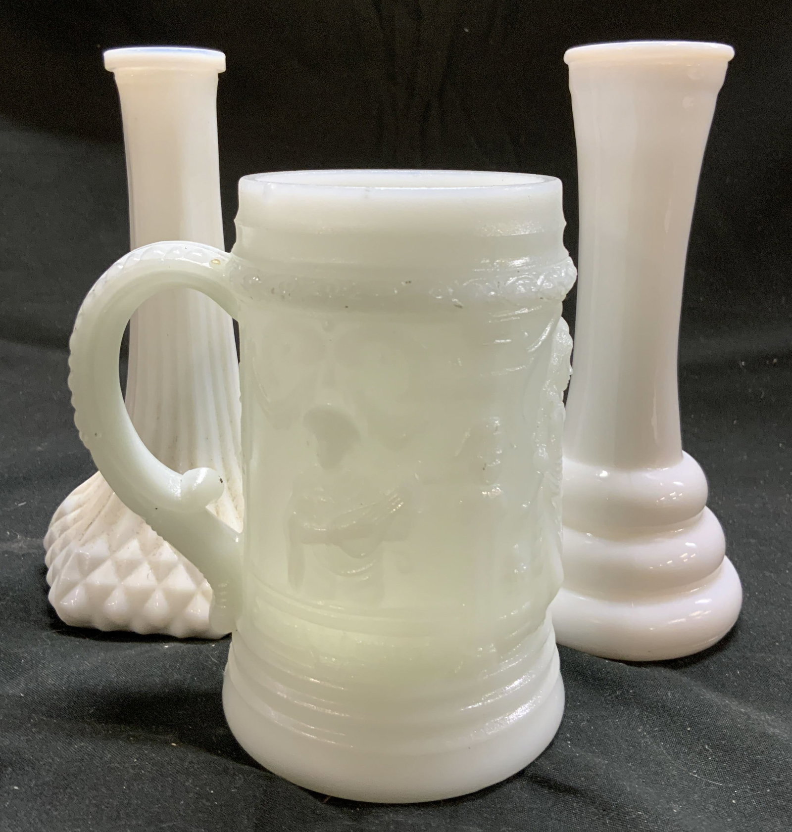 Vintage Milk Glass Bud vases & Mug: Lot includes 2 Bud vases & 1 mug. Each are white toned milk glass. Pieces each appear to be vintage. Mug has beveled figural detail. Largest vase measures approx 6 inches tall 2.75 inches wide. Mug, v