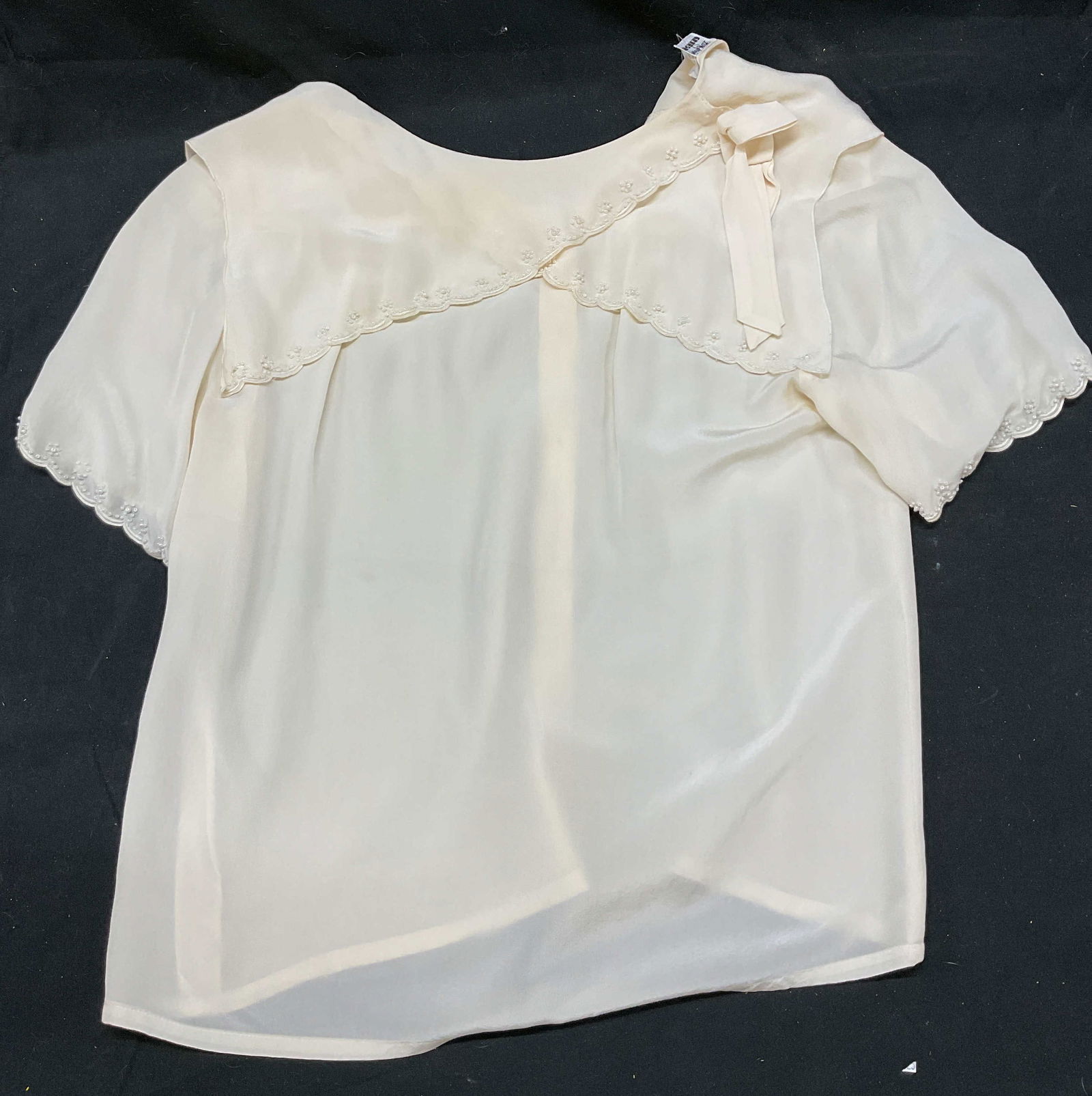 Vtg Bon Genie Grieder Cream Silk Top: Vintage Bon Genie Grieder cream silk top. Layered collar. Scalloped trim design on collar and sleeves. Ribbon accent on shoulder. Small pearl accents. Button down back. 100% pure silk. 18 inches acros