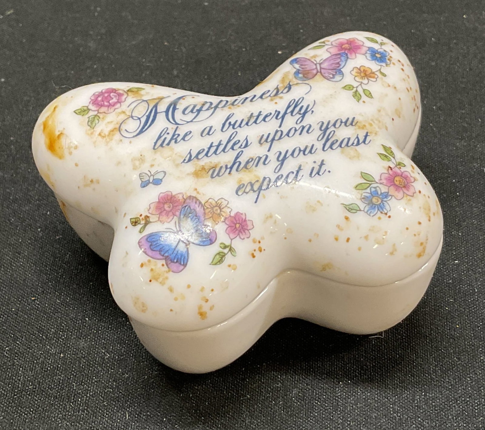 Vtg 1974 AVON Butterfly Porcelain Trinket Box: Vintage 1974 AVON butterfly porcelain trinket box. Text in script typeface reads happiness, like a butterfly settles upon you when you least expect it. Floral patterns. Porcelain trinket box with lid.
