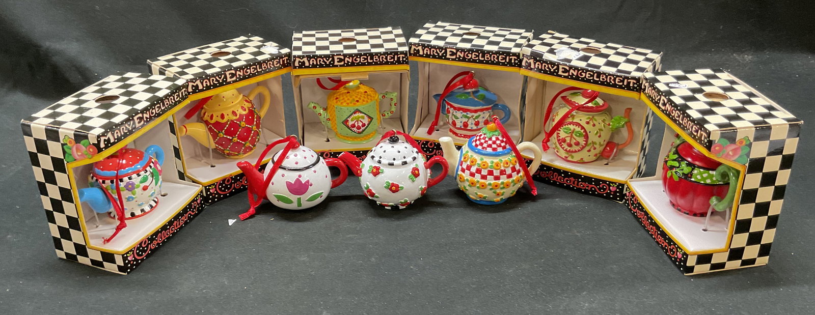 Set 9 Mary Engelbreit Ink Tea Pot Ornaments: Set of 9 Mary Engelbreit Ink tea pot ornaments. Each tea pot has ribbon for hanging attached. Miniature decorative tea pots. Tea pot measures 2.5 x 1.5 inches. Box measures 3.75 x 3.25 x 2.25 inches. 