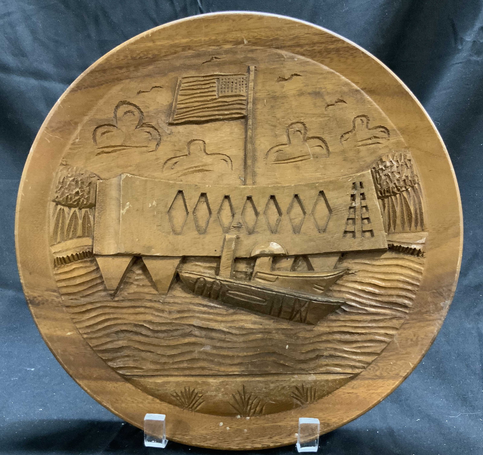ALOHA Hand Carved Wooden Hawaiian Souv Plate: Tag on backside reads ALOHA SURFRIDER CAMERA & GIFT SHOP WAIKIKI HAWAII. Plate is tan toned and wooden. Appears to be hand carved. Piece has depiction of ship, landscape & American flag. Piece measure